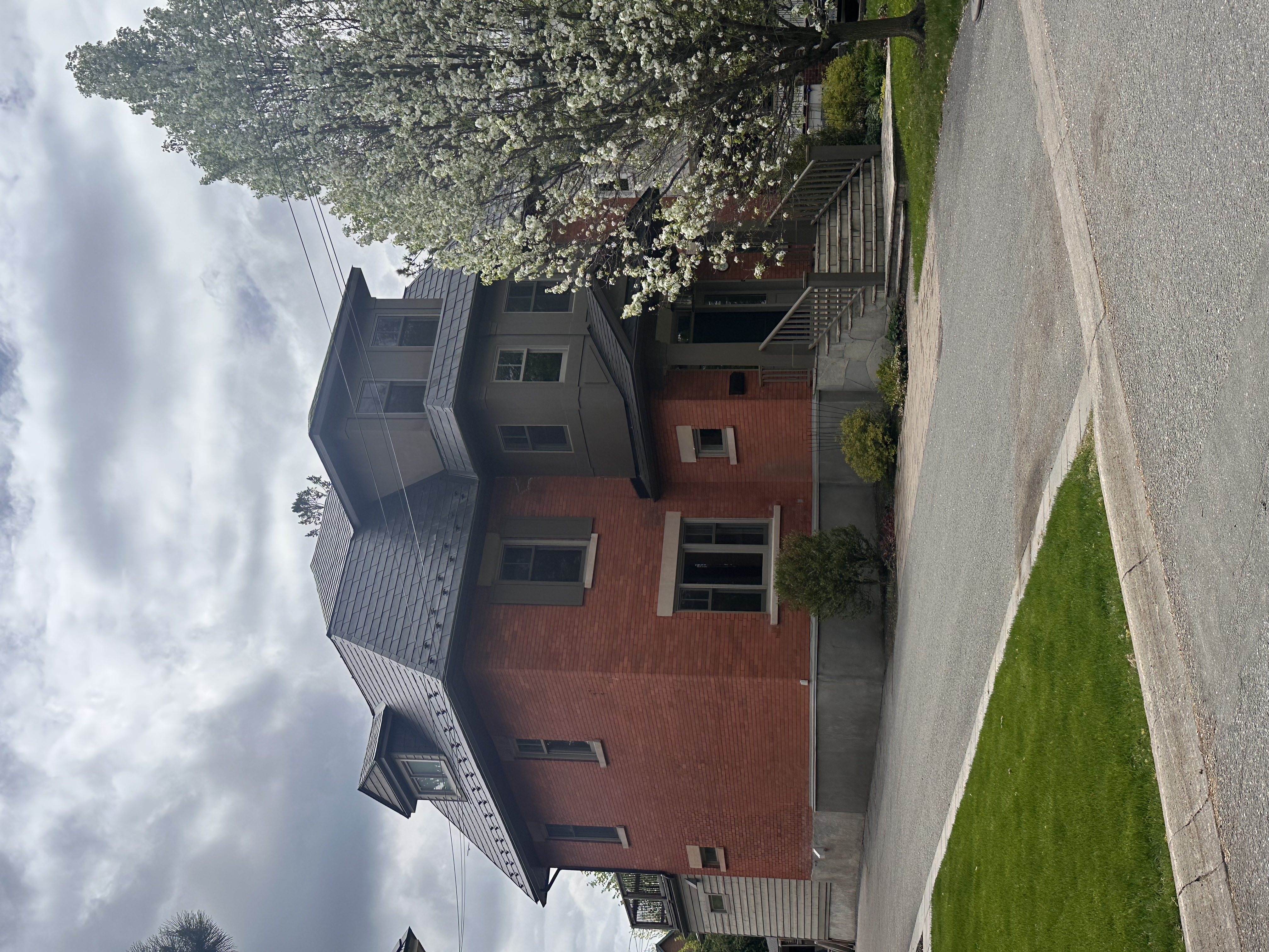 Heritage red-brick home in Ottawa with a dark charcoal Interlock aluminum slate mansard roof featuring dormers, viewed from the front-left.