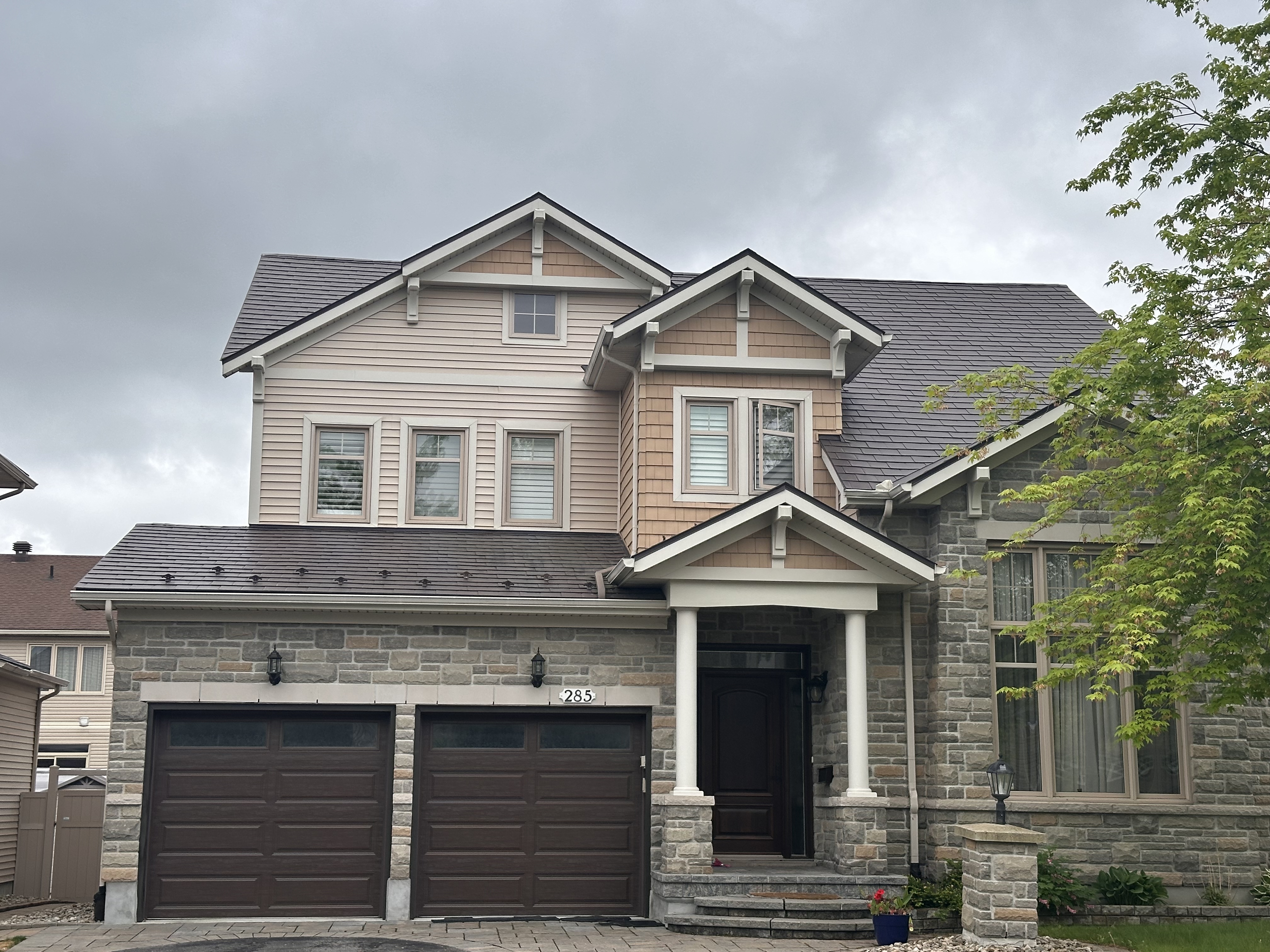 Two-storey Craftsman home in Ottawa with Interlock Tudor Brown aluminum slate metal roofing, stone facade, double garage, and decorative dormers.