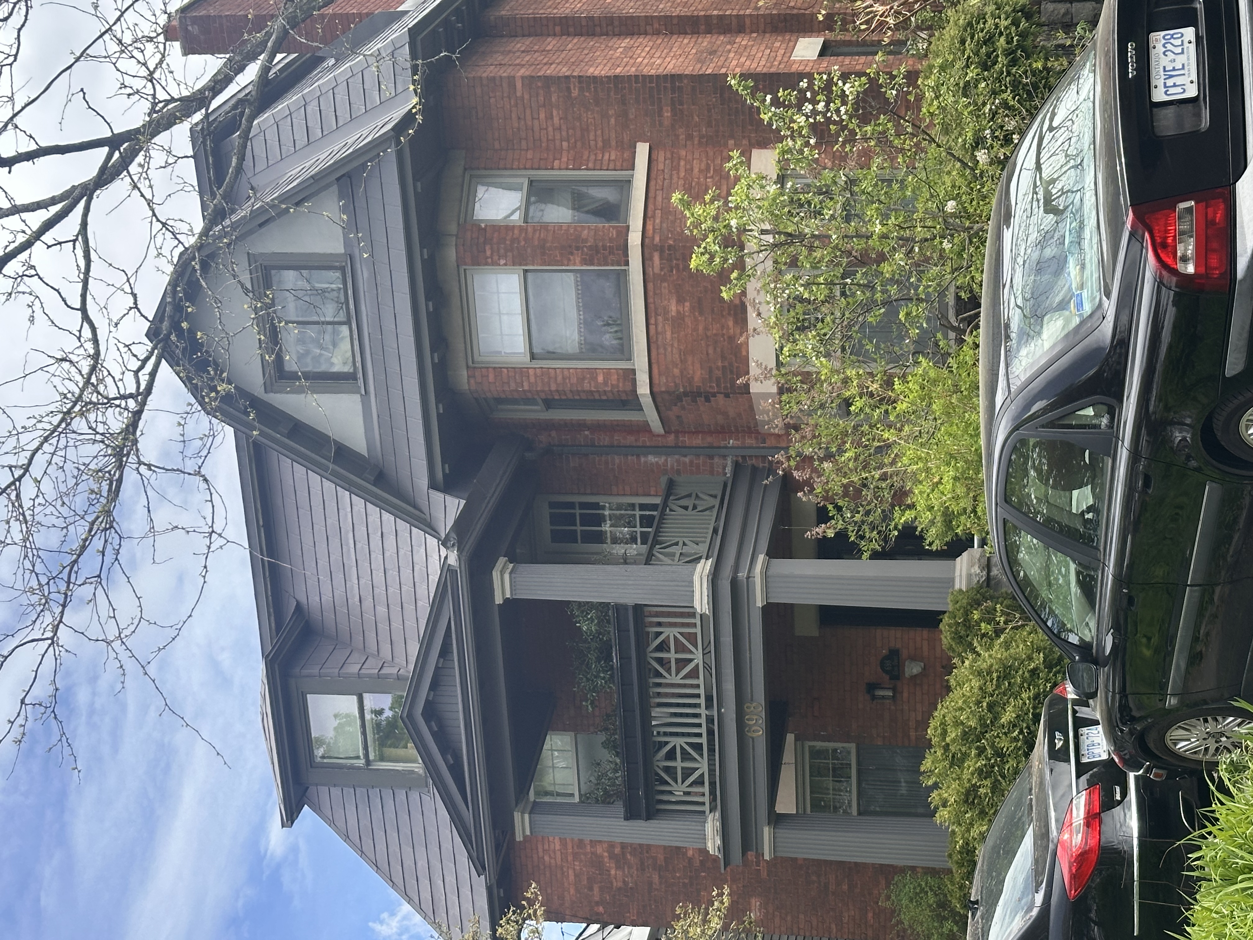 Three-storey Victorian red-brick home in Ottawa with Interlock Musket Grey aluminum slate roofing, multiple dormers, and a covered balcony entry.