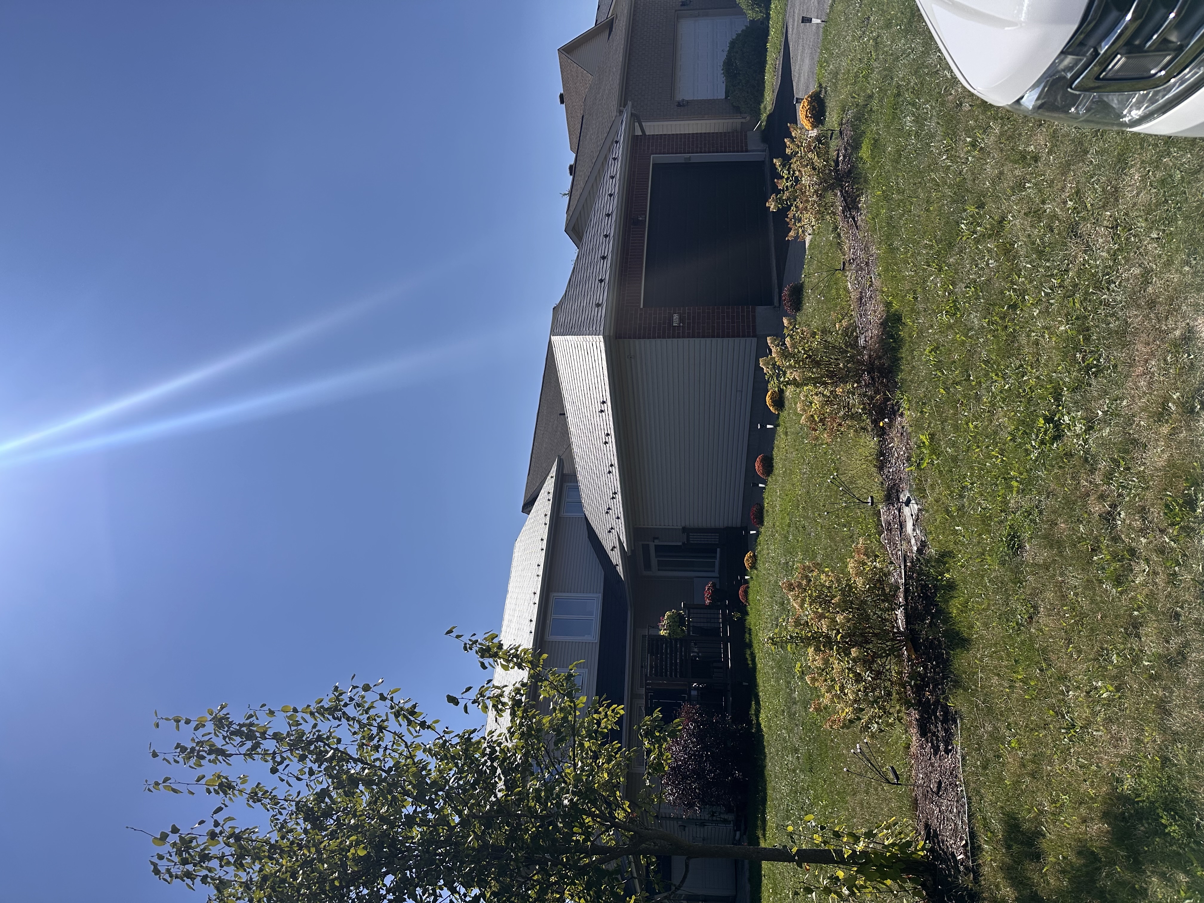 Two-storey suburban home with Interlock black aluminum slate metal roofing across multi-hip profiles, brick and vinyl siding, Ottawa ON.