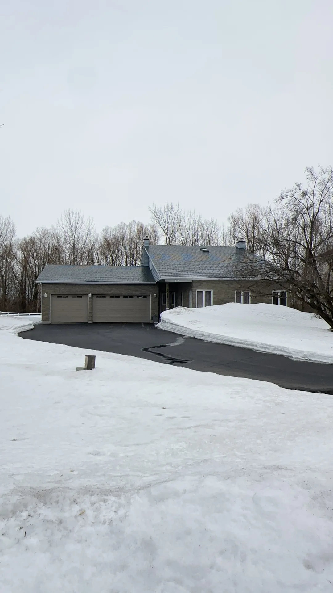 Black Interlock Slate aluminum roof on a rural home with a grey metal roof and attached garage in, Navan, Ontario