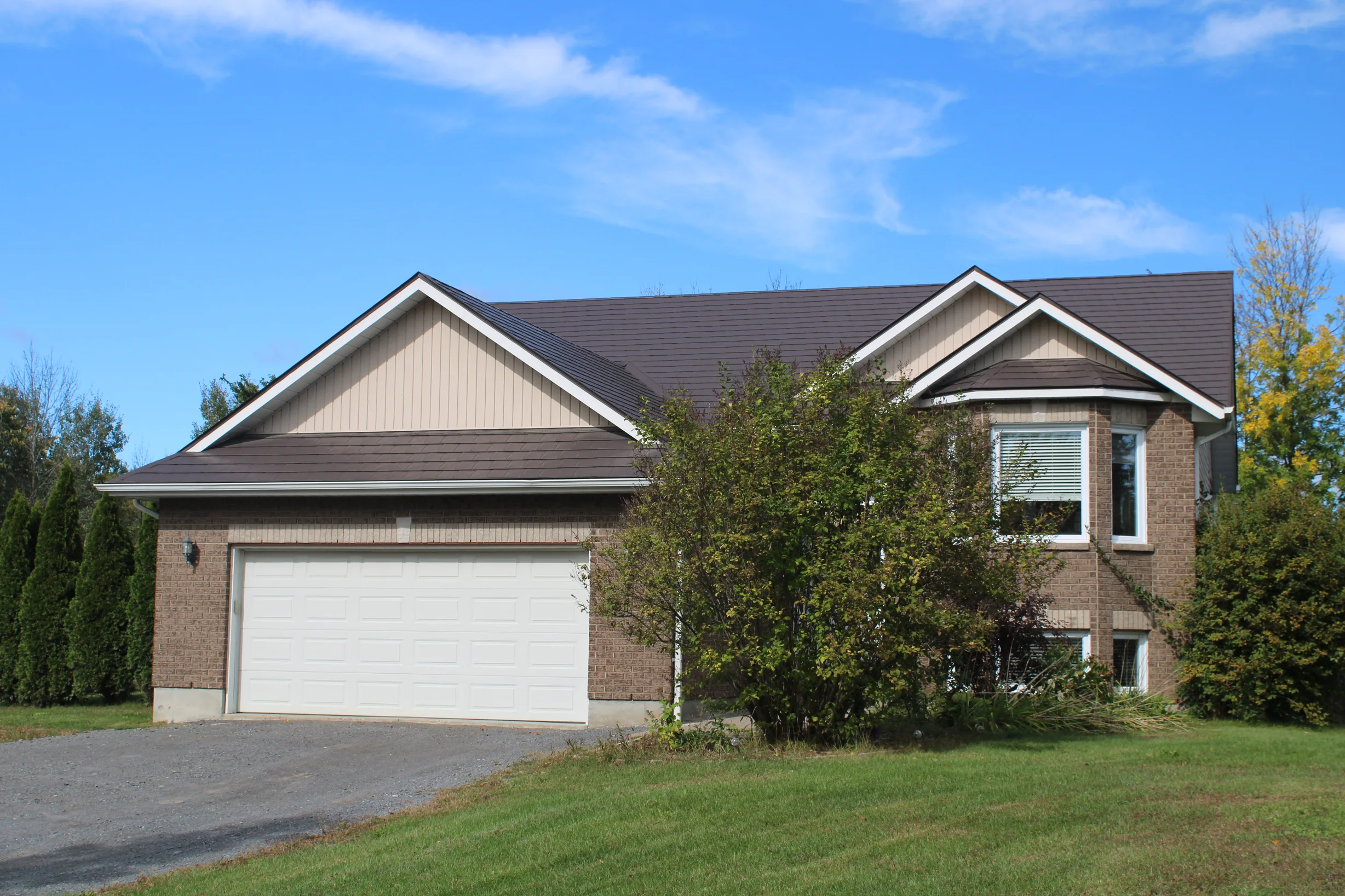 Tudor Brown Interlock Slate aluminum roof on a brown Tudor-style home with dormers in a suburban setting, Kingston, Ontario