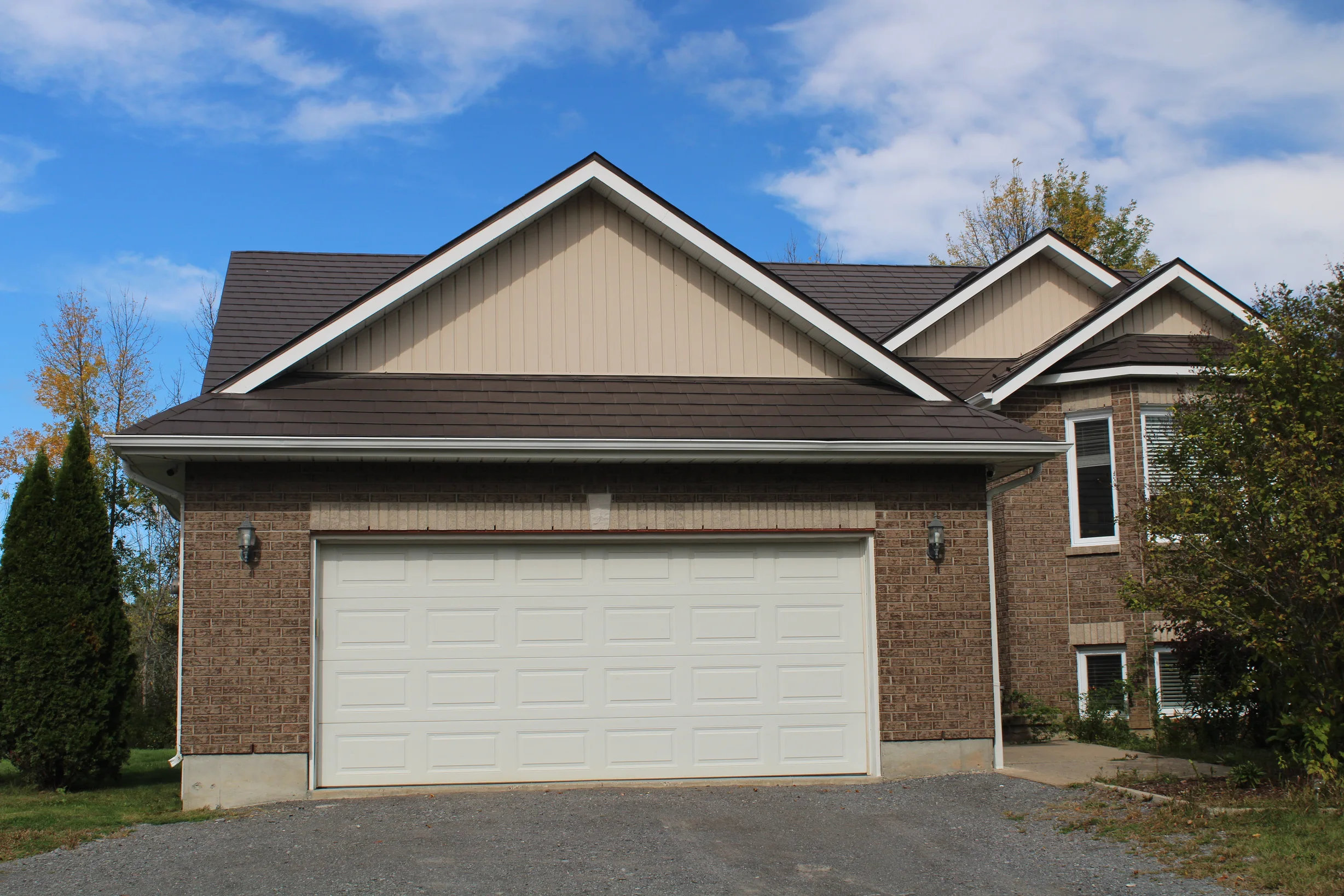 Tudor Brown Interlock Slate aluminum roof on a brown two-storey Tudor home with dormers in a rural, Kingston, Ontario
