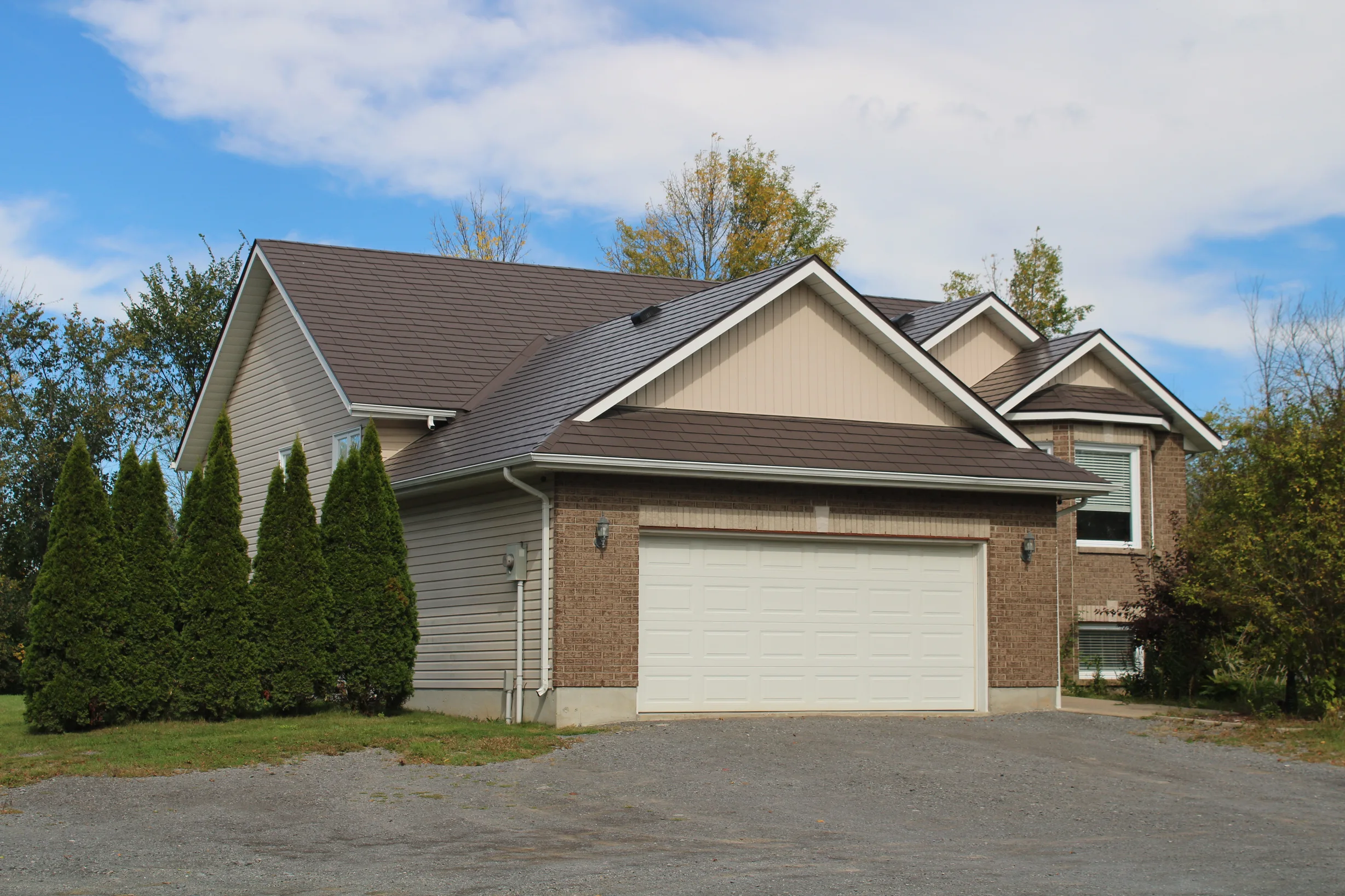 Tudor Brown Interlock Slate aluminum roof on a brown two-storey Tudor home with dormers and brick, Kingston, Ontario