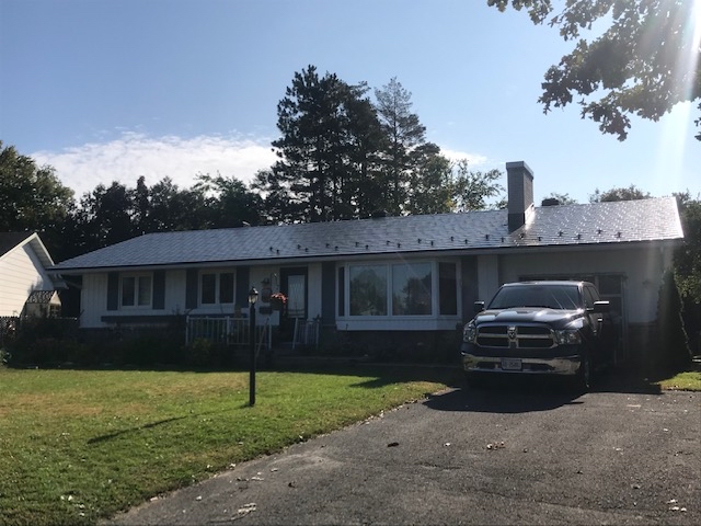 Single-storey ranch home in Ottawa with a low-pitch deep charcoal Interlock aluminum slate metal roof, chimney, and attached garage.