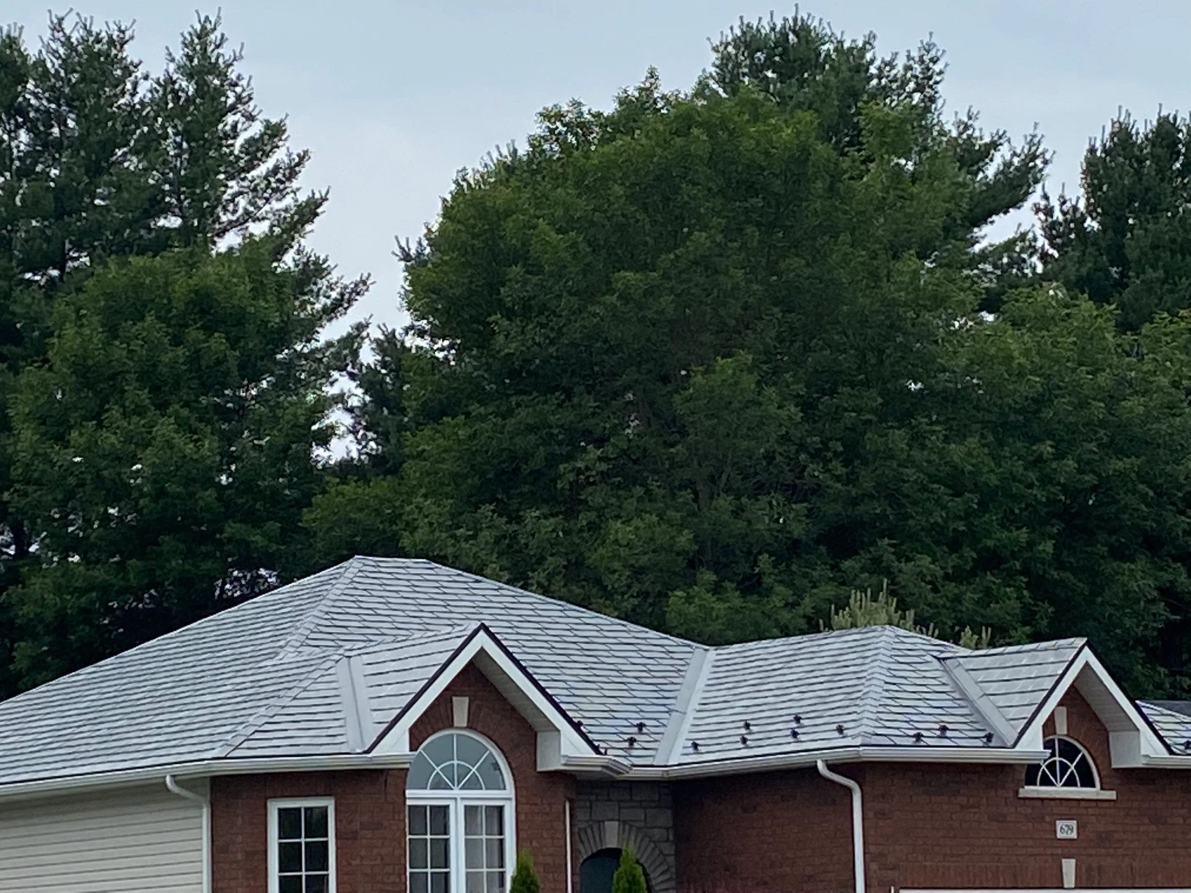 Black Interlock Slate aluminum roof on a red brick home with a metal roof in a wooded suburb, Pembroke, Ontario