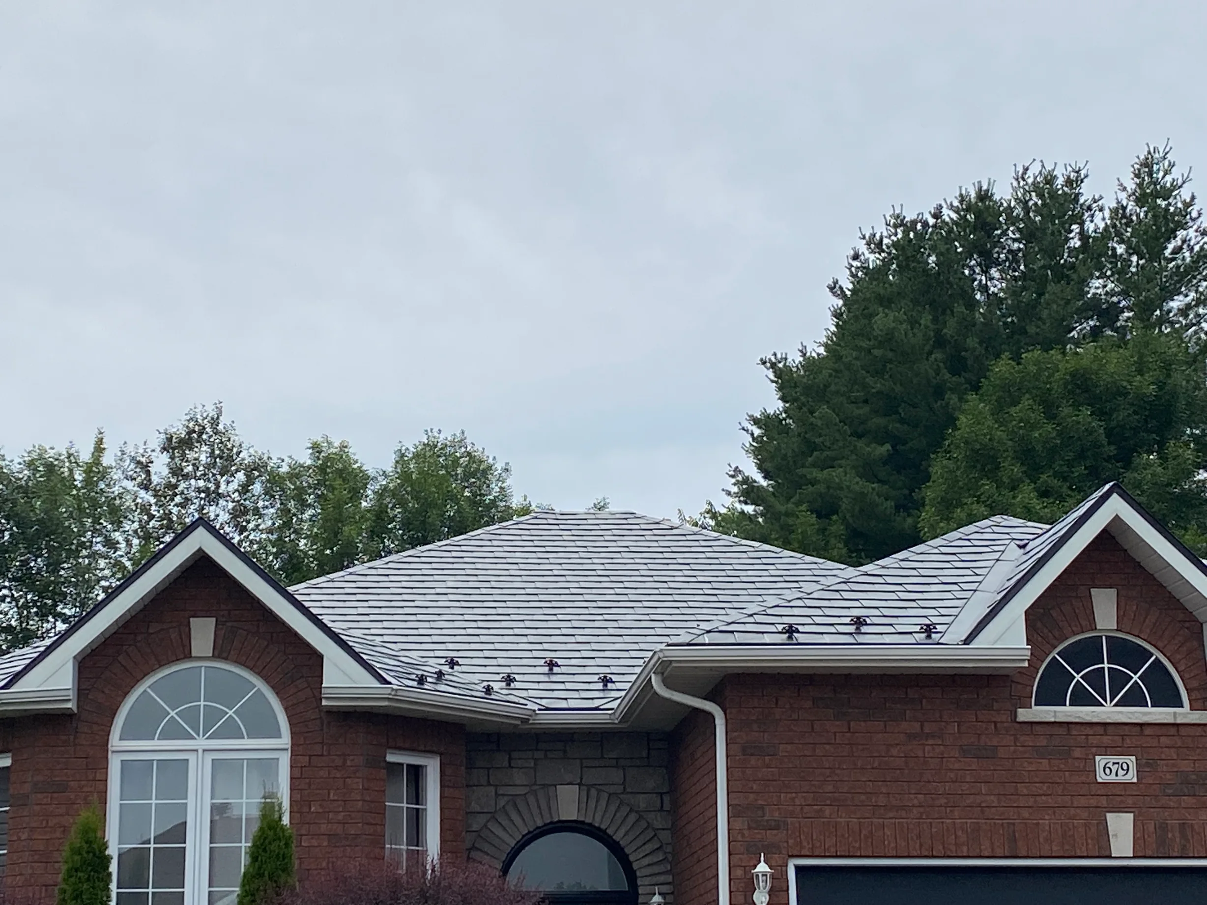 Black Interlock Slate aluminum roof on a red brick single-family home with a metal roof in rural, Pembroke, Ontario