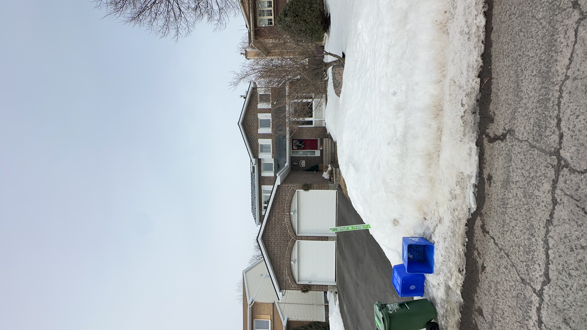 Two-storey brick home in Orleans ON with Interlock deep charcoal aluminum slate metal roof, double garage, shot from across snowy street.
