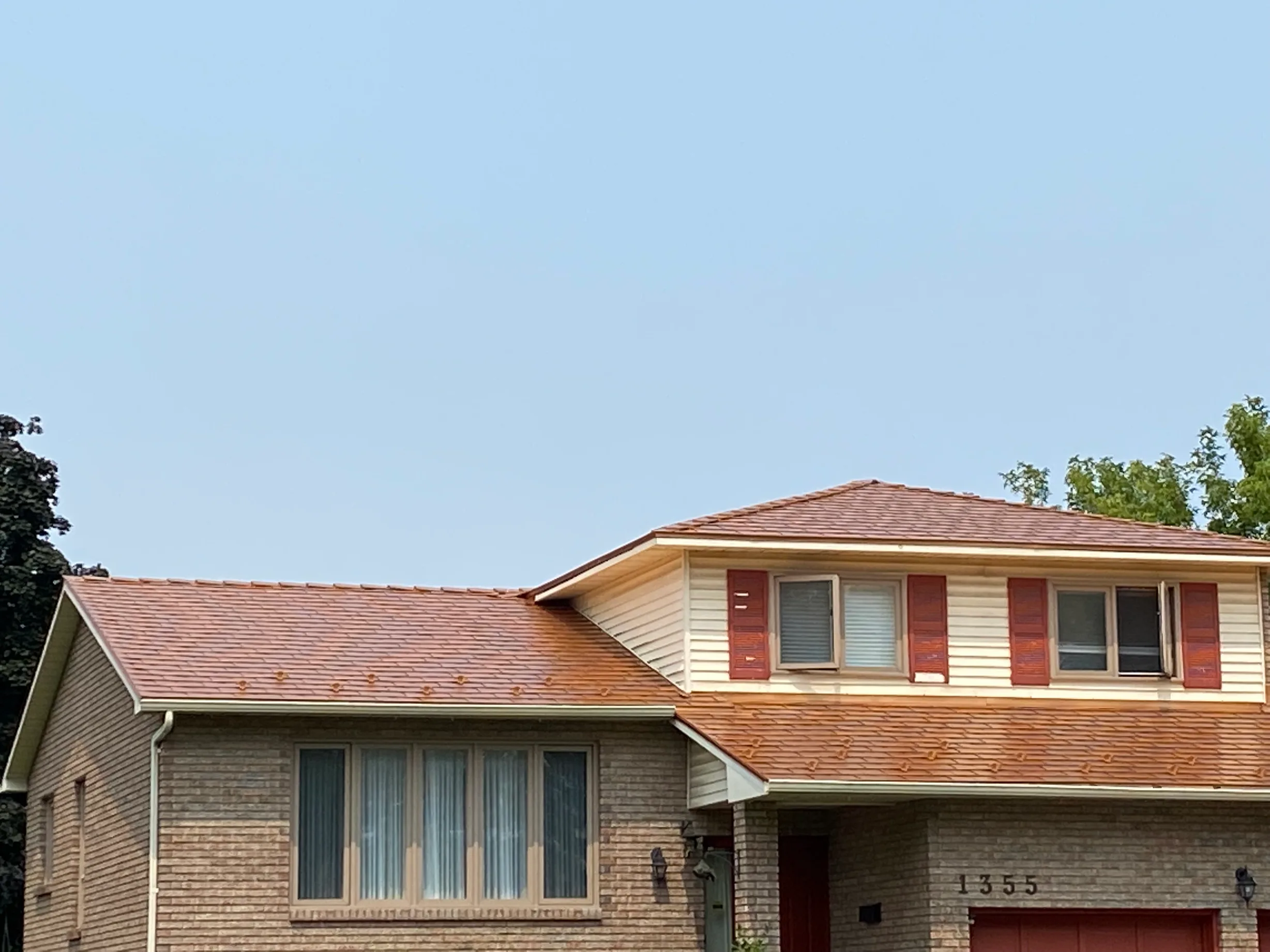 Copper Penny Interlock Slate aluminum roof on a cream-coloured home with red shutters and a red door, Gloucester, Ontario