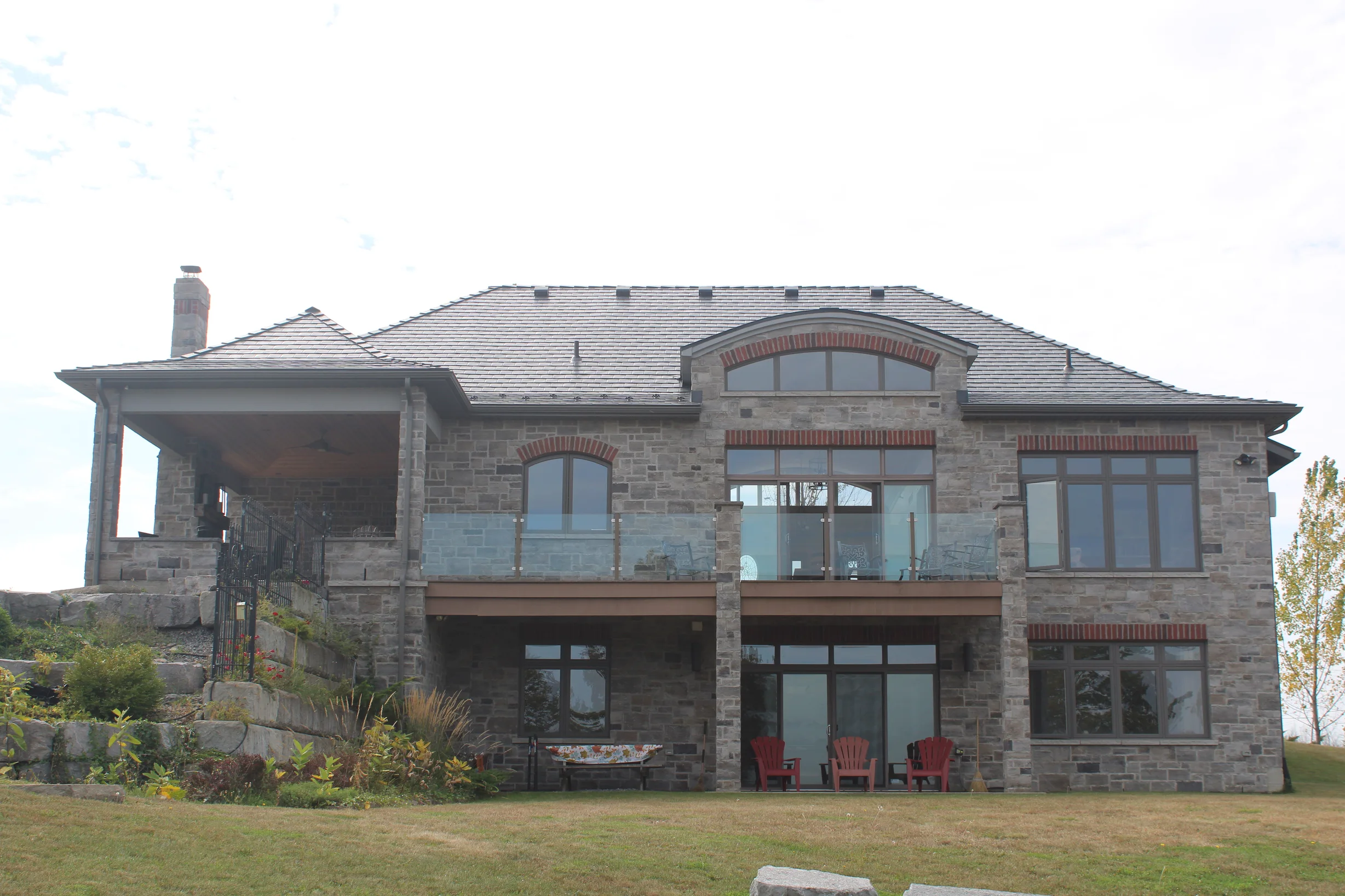 Deep Charcoal Interlock Slate aluminum roof on a two-storey home with a metal roof among tall pines, Picton, Ontario