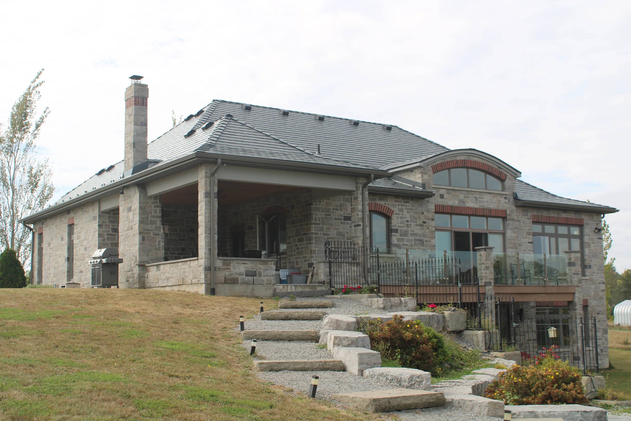 Deep Charcoal Interlock Slate aluminum roof on a modern home with a stone facade on a rural property, Picton, Ontario