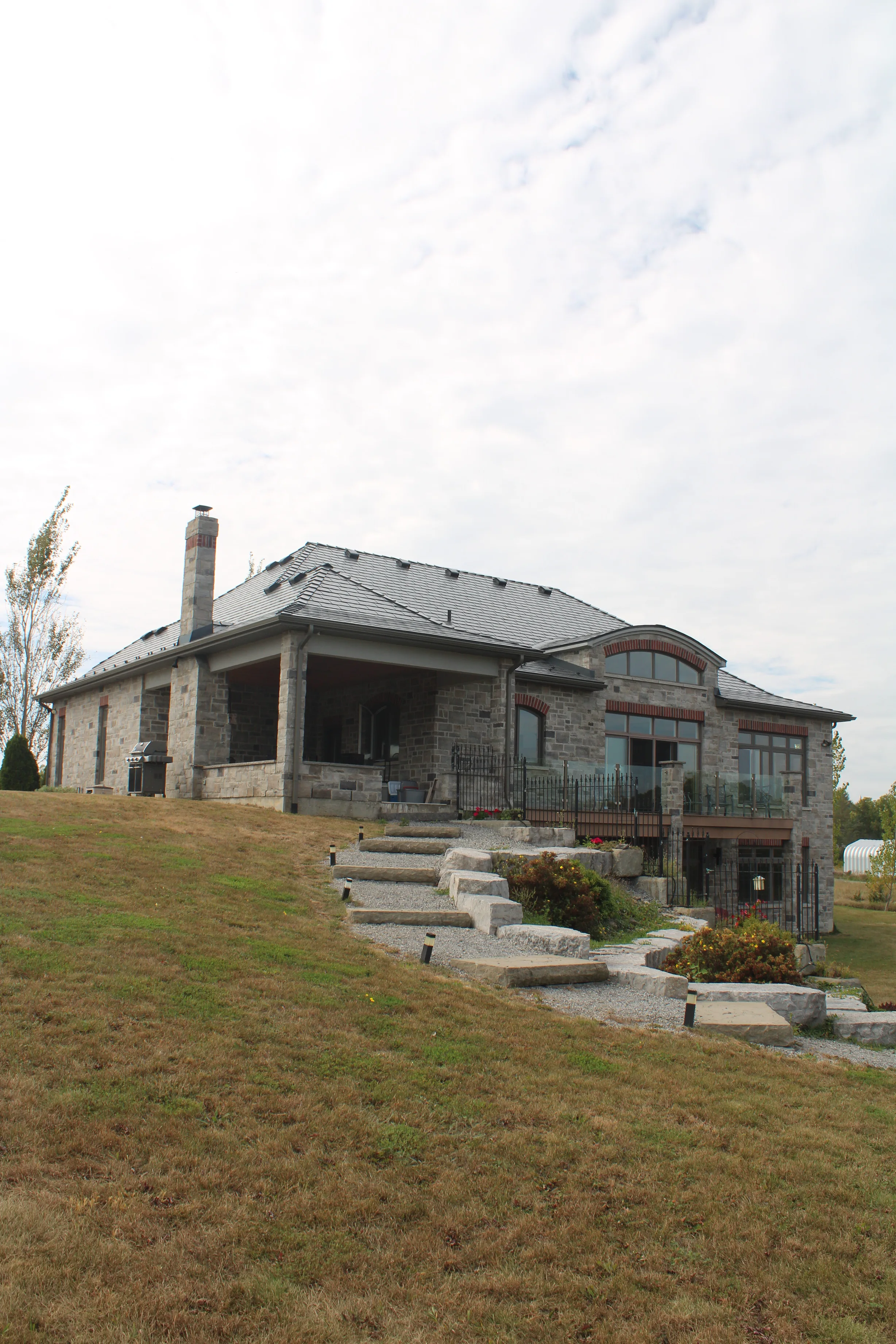 Deep Charcoal Interlock Slate aluminum roof on a Deep Charcoal metal roof on a stone house in a rural, Picton, Ontario