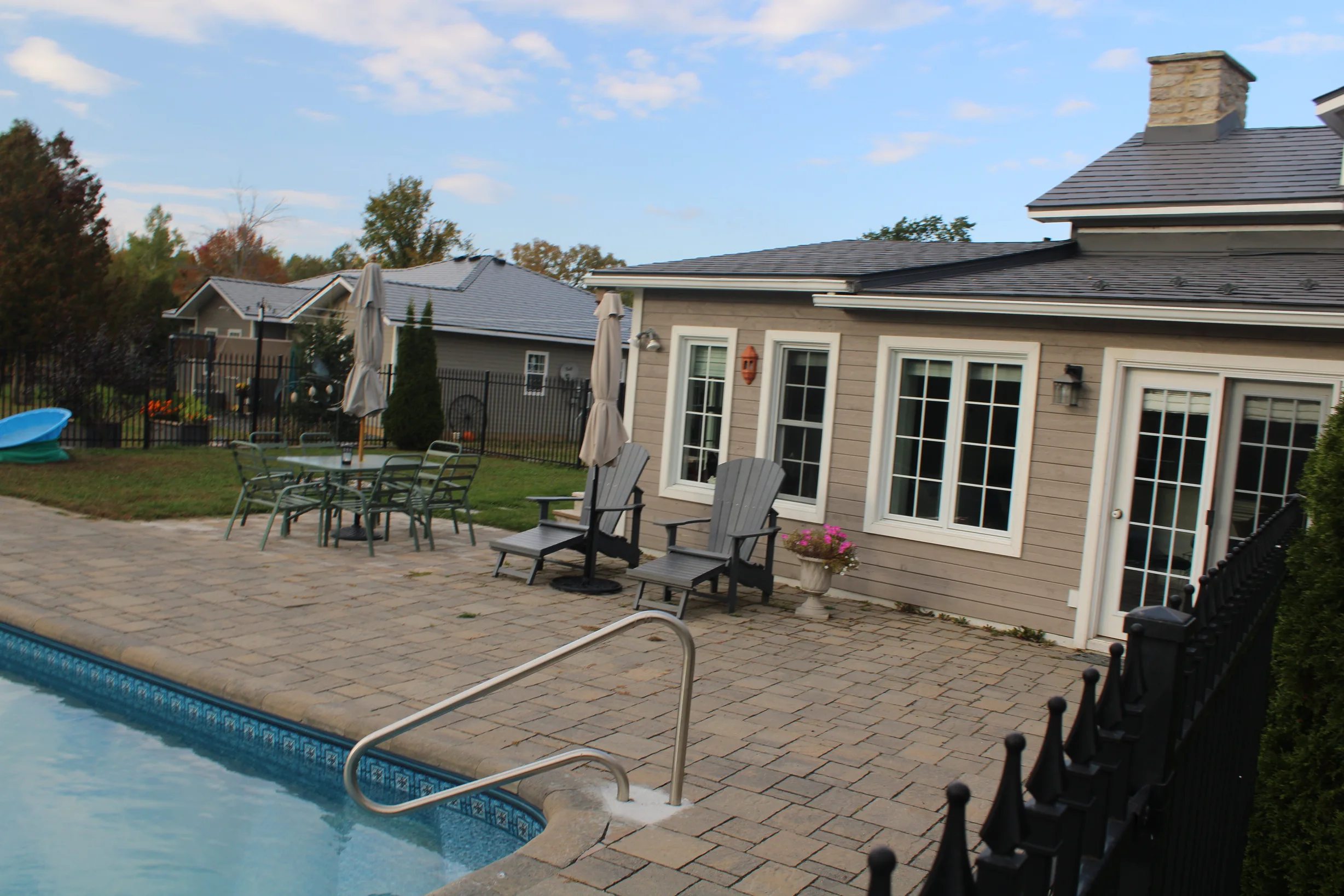 Deep Charcoal Interlock Slate aluminum roof on a tan home with a metal roof among tall trees, Carleton Place, Ontario