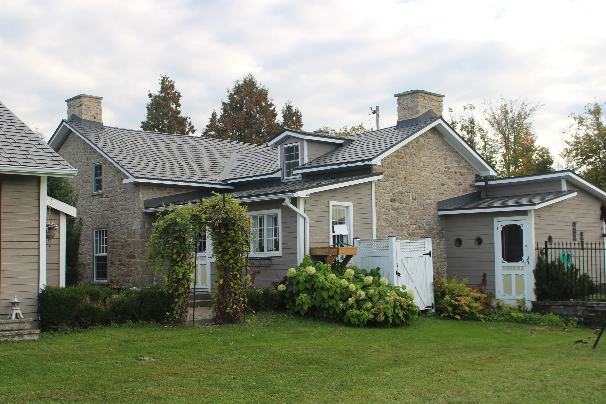 Deep Charcoal Interlock Slate aluminum roof on a tan home with white trim and a metal roof in a rural, Carleton Place, Ontario