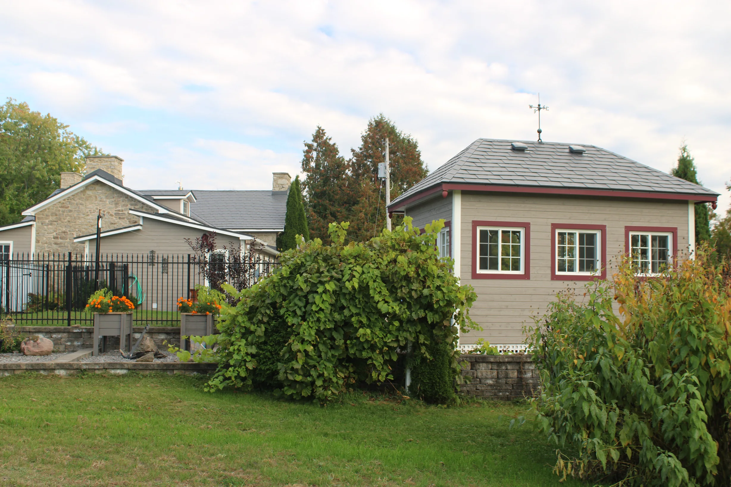 Deep Charcoal Interlock Slate aluminum roof on a beige home with a metal roof and two windows among tall, Carleton Place, Ontario
