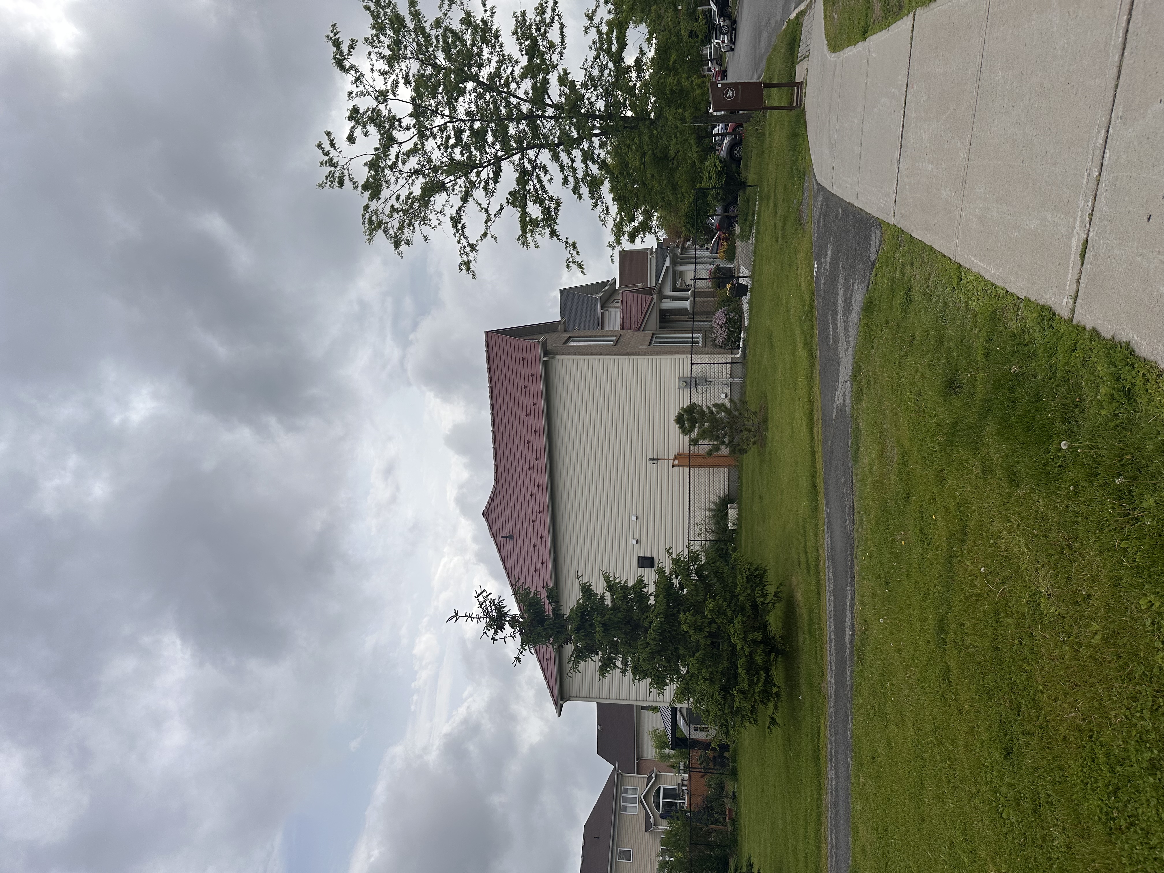 Street view of a two-storey suburban home in Ottawa with Interlock aluminum slate roofing in Tile Red, viewed from across a sidewalk.