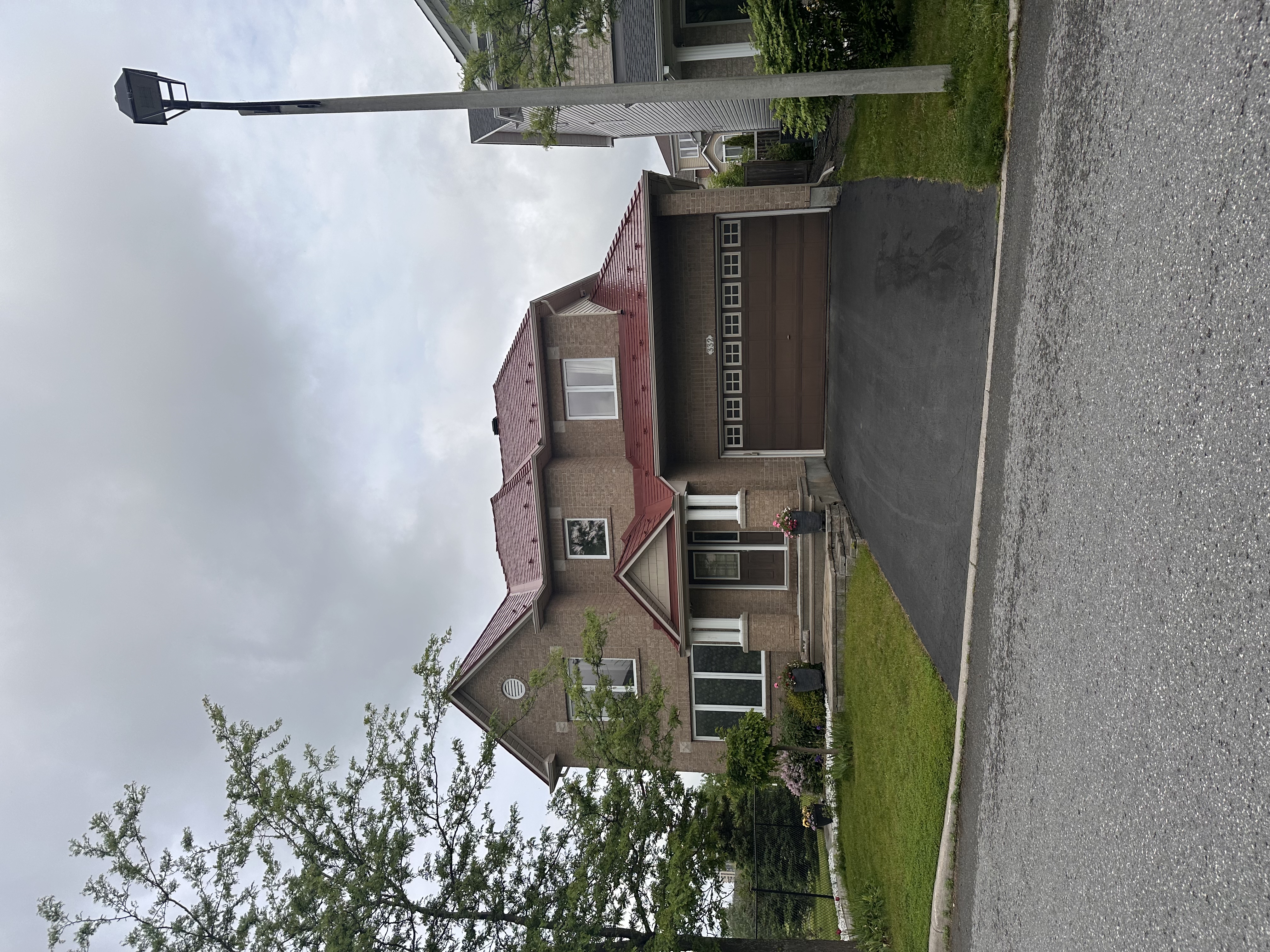Two-storey brick Colonial home in Ottawa with a multi-hip Interlock aluminum slate roof in Tile Red, featuring a double garage and covered entry.