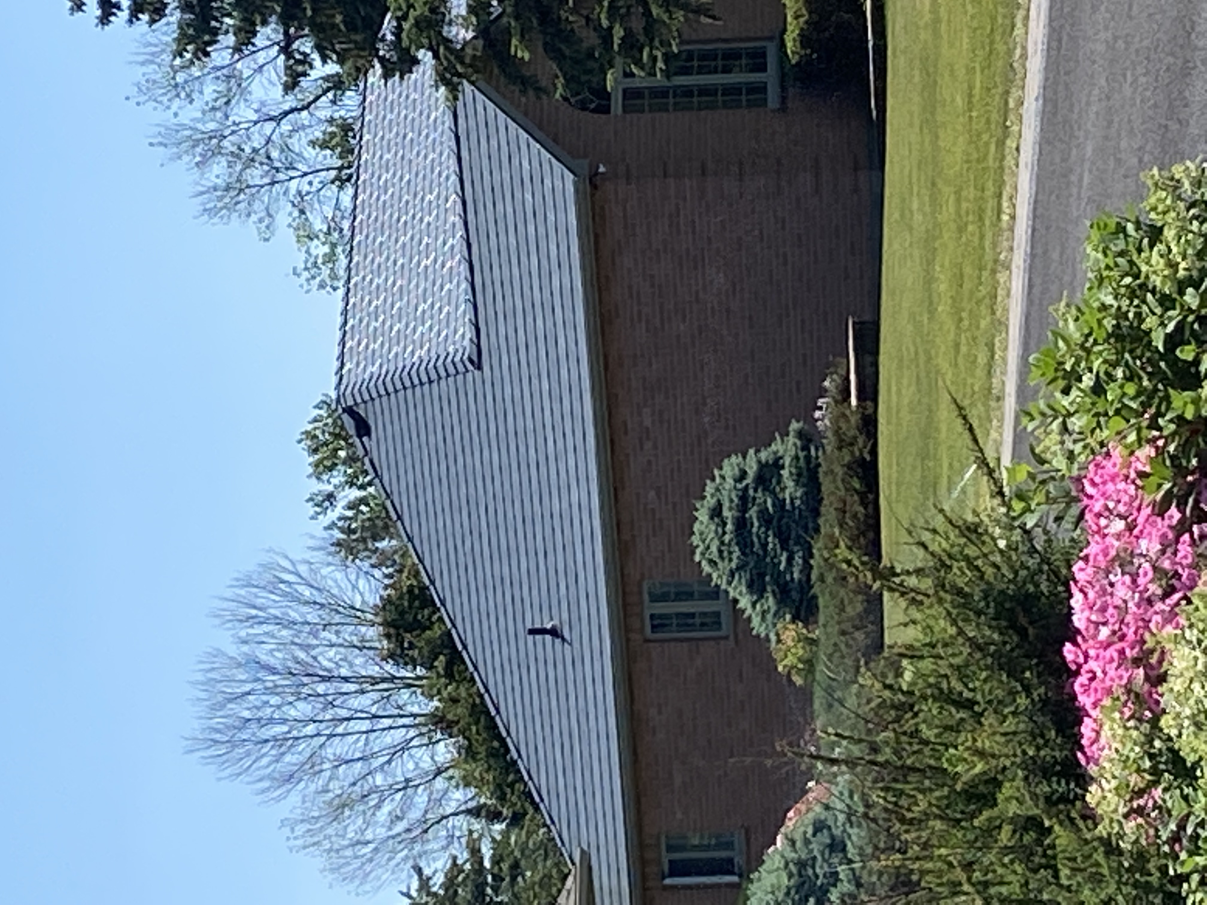 Single-storey brick Colonial home in Cornwall, ON with a hip-style Interlock aluminum slate roof in Deep Charcoal, surrounded by mature trees and manicured landscaping.