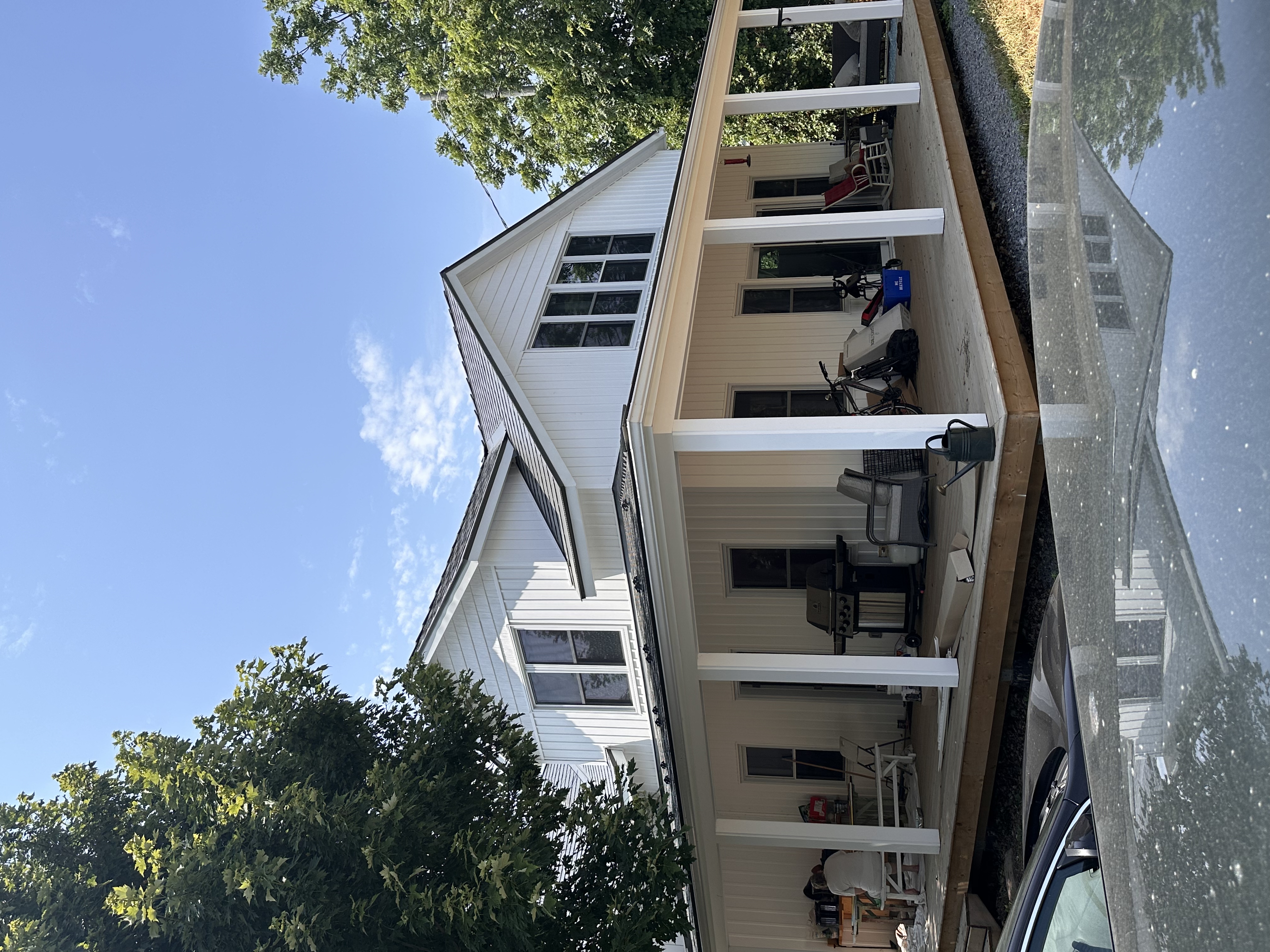 Modern farmhouse in Bloomfield ON with Interlock Musket Grey aluminum slate roofing, wraparound porch, and dormer windows.