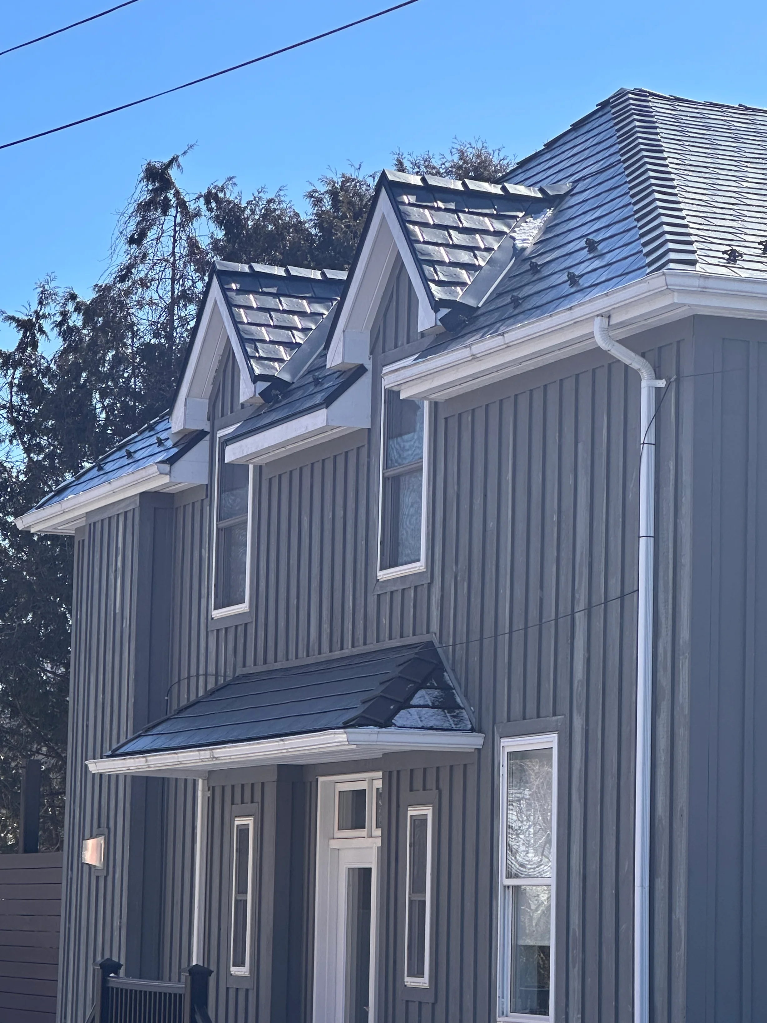 Black Interlock Slate aluminum roof on a grey two-storey colonial home with dormers in a suburban, Prince Edward, Ontario