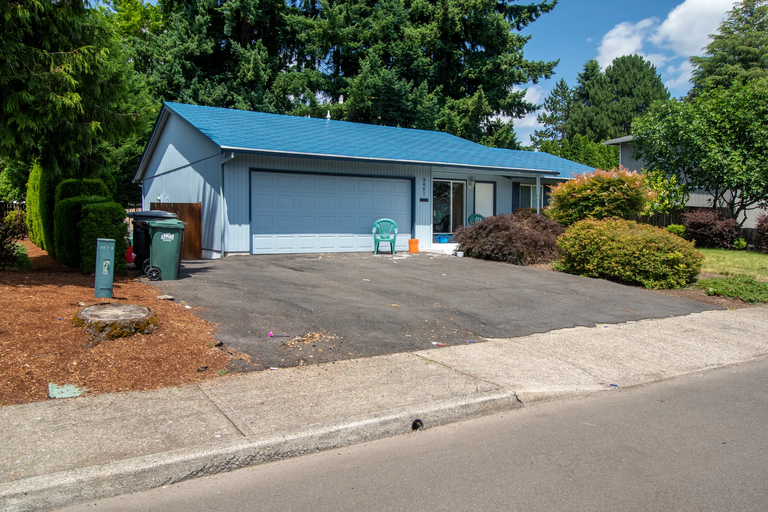 Royal Blue Interlock Shingle aluminum roof on a blue ranch style home with a metal roof among tall trees, Hillsboro, Oregon