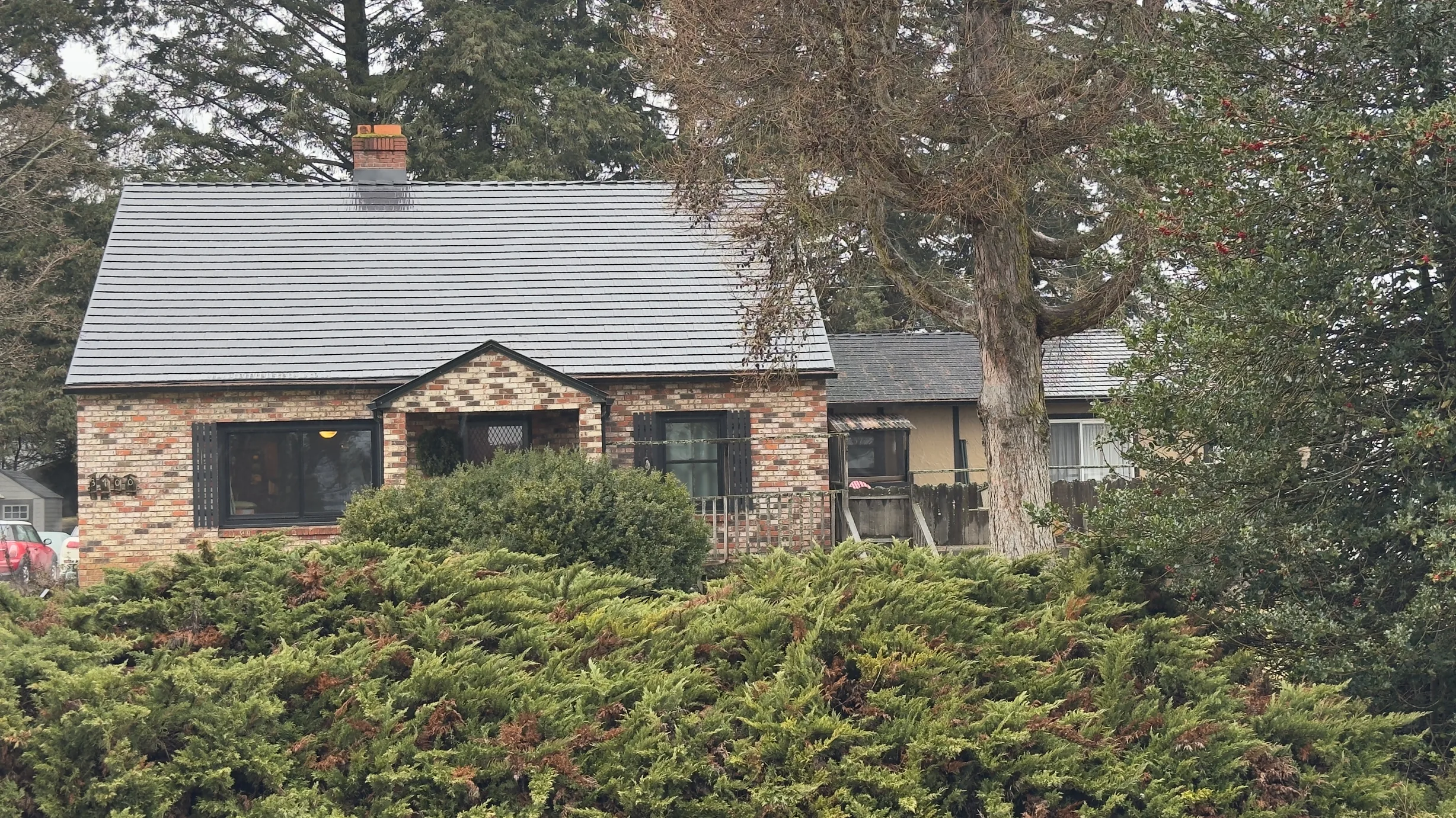 Black Interlock Cedar Shingle aluminum roof on a brown one-storey cottage with a metal roof in a forested, Hood River, Oregon