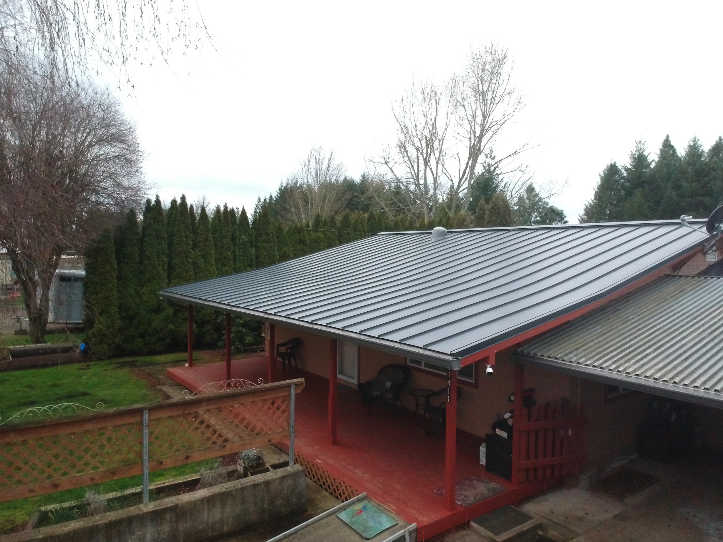 Deep Charcoal Interlock Standing Seam aluminum roof on a red single-family home with a metal roof in a forested, Scio, Oregon