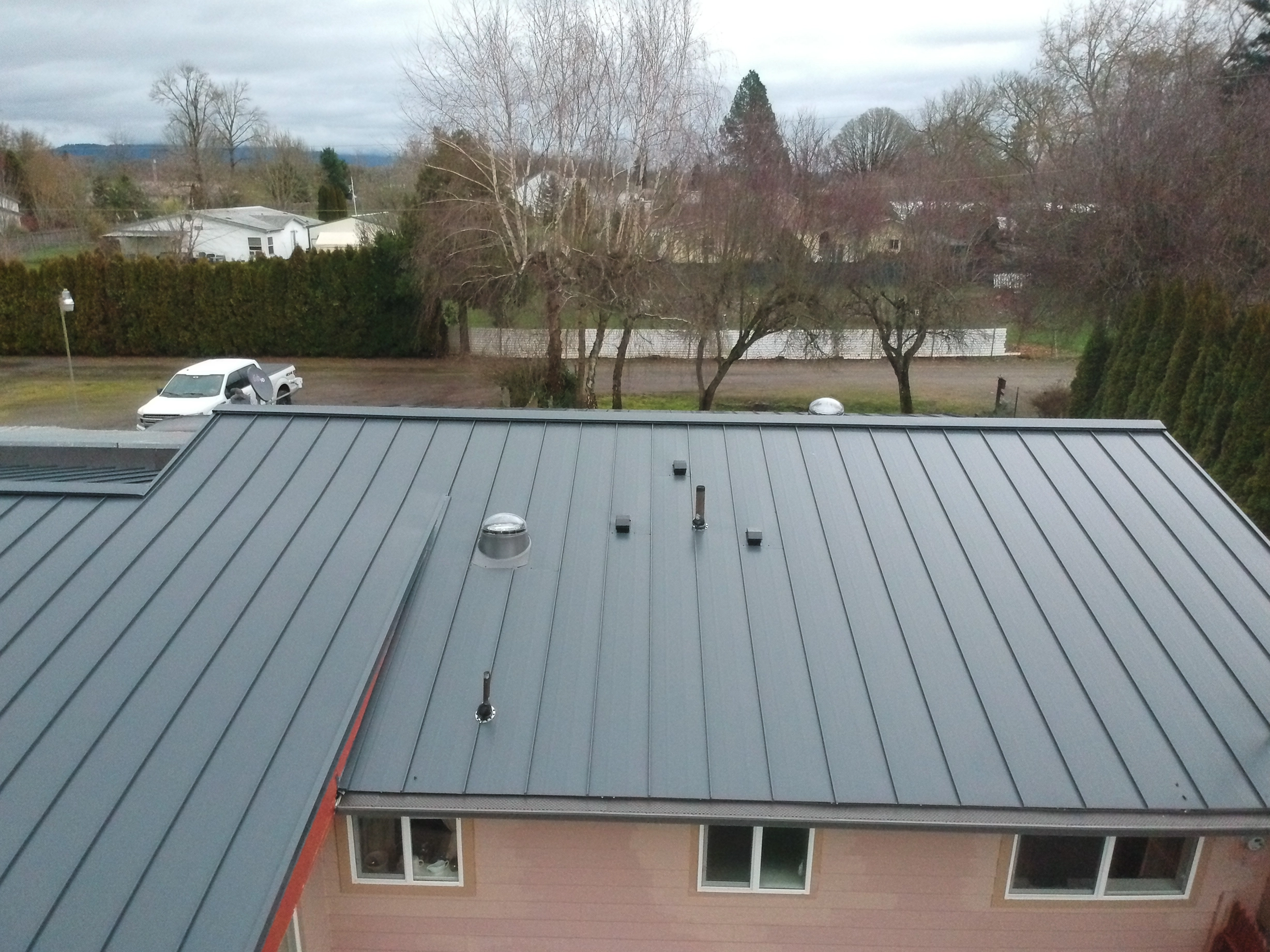 Deep Charcoal Interlock Standing Seam aluminum roof on a pink house with a metal roof in a rural area, Scio, Oregon