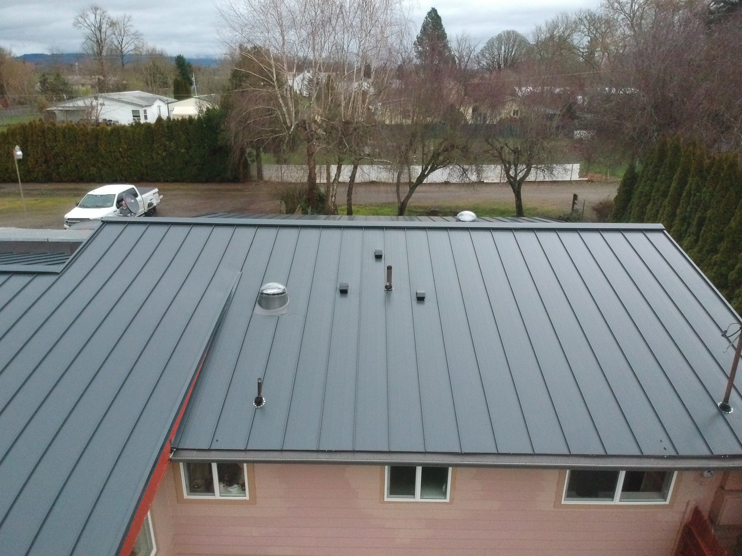 Deep Charcoal Interlock Standing Seam aluminum roof on a single-story home with a metal roof in a rural wooded area, Scio, Oregon