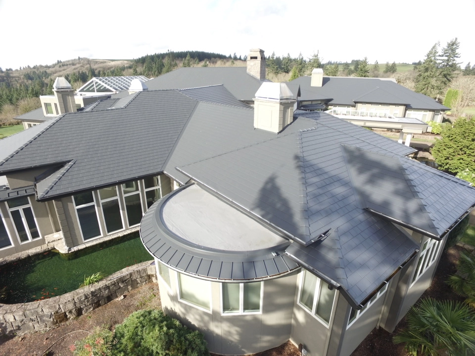 Deep Charcoal Interlock IB Membrane aluminum roof on a beige single-family home with a metal roof in a forested, Turner, Oregon