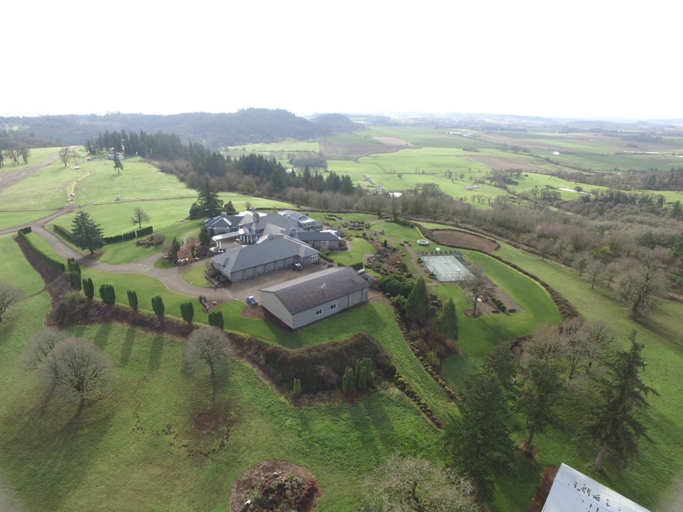 Deep Charcoal Interlock IB Membrane aluminum roof on a two-storey home with a metal roof among tall pines, Turner, Oregon