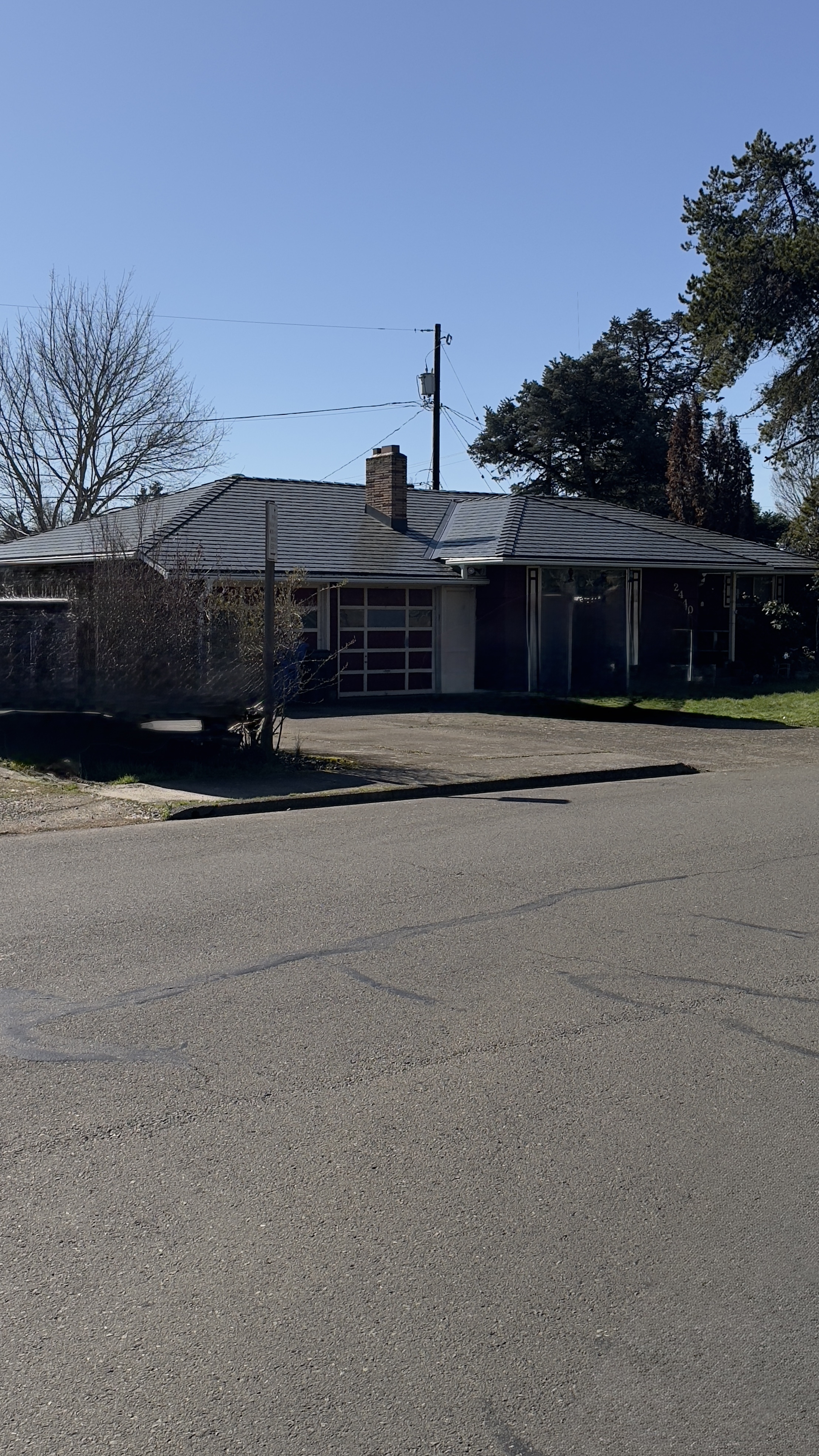 Single-story ranch home in Salem, OR with a multi-hip deep charcoal Interlock aluminum slate metal roof and brick chimney, viewed from across the street.