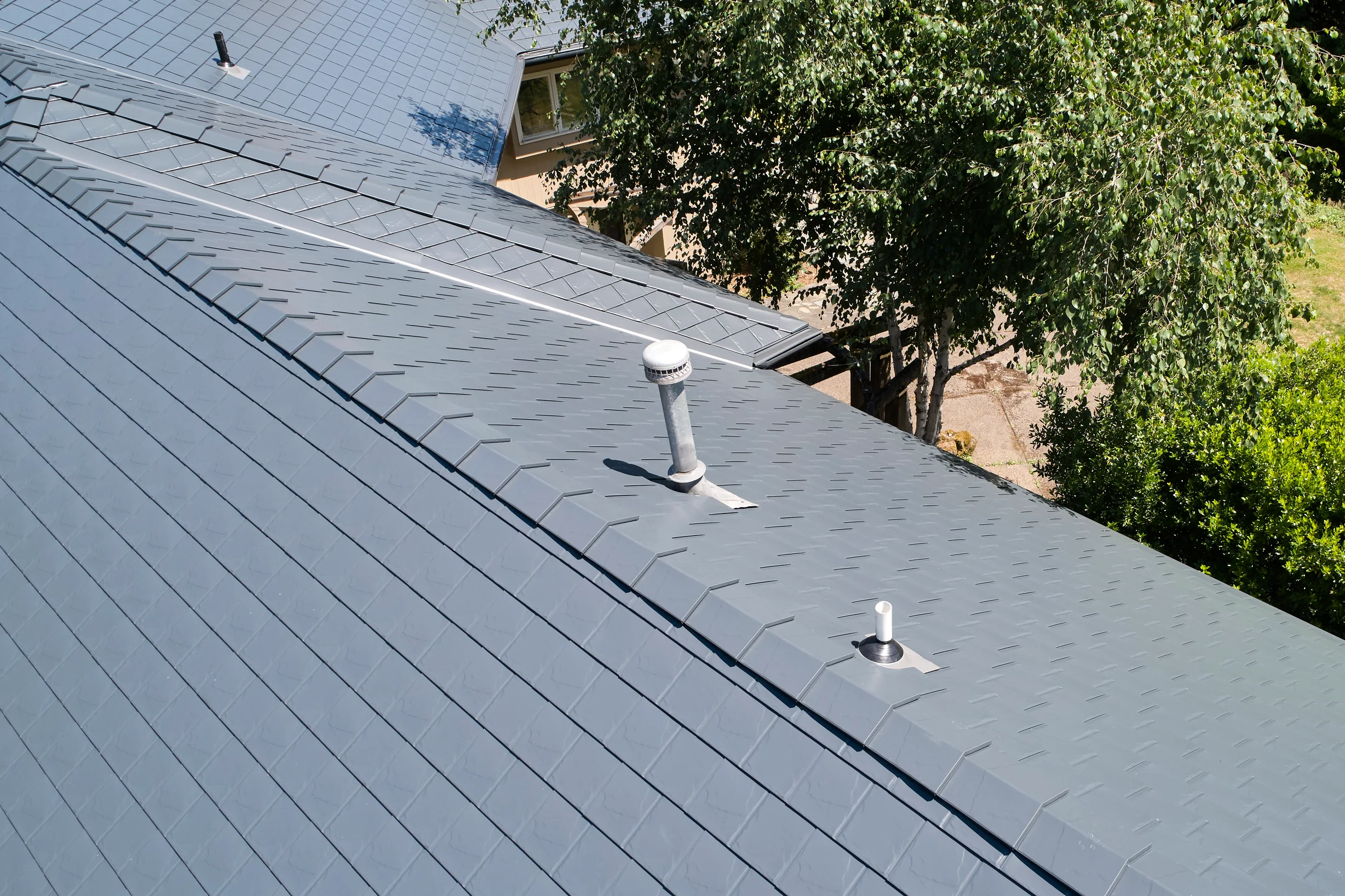 Deep Charcoal Interlock Slate aluminum roof on a single-family home with a metal roof in a forested area, Portland, Oregon