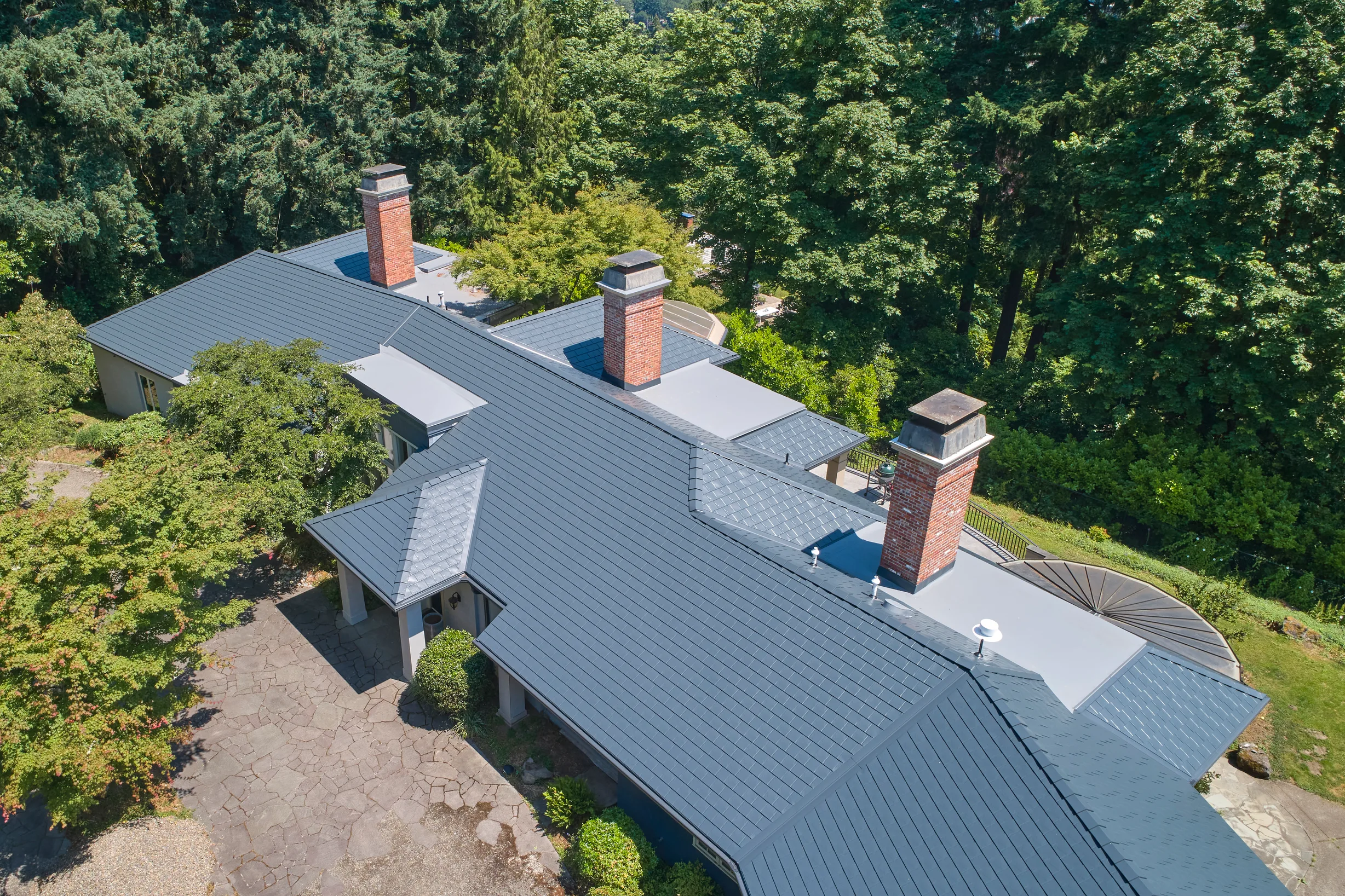 Deep Charcoal Interlock Slate aluminum roof on a single-storey home with a metal roof in a forested setting, Portland, Oregon