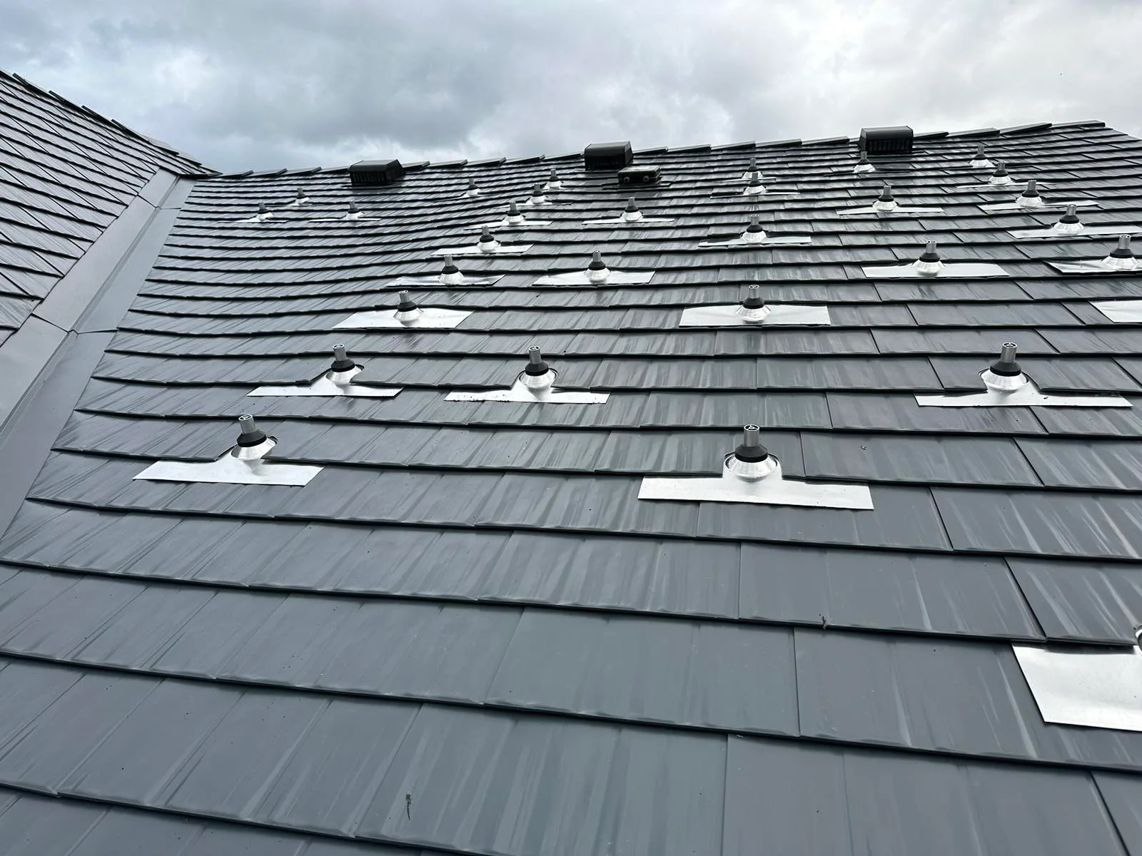 Deep Charcoal Interlock Cedar Shingle aluminum roof on a grey home with a metal roof among tall pines, Newberg, Oregon