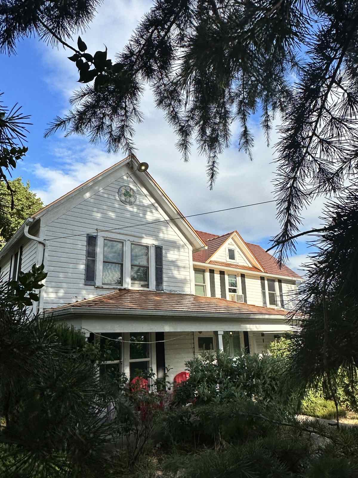 Two-story Victorian home in McMinnville, OR with Interlock Copper Penny cedar-shingle aluminum metal roofing, steep gabled dormers, and a wrap-around porch.