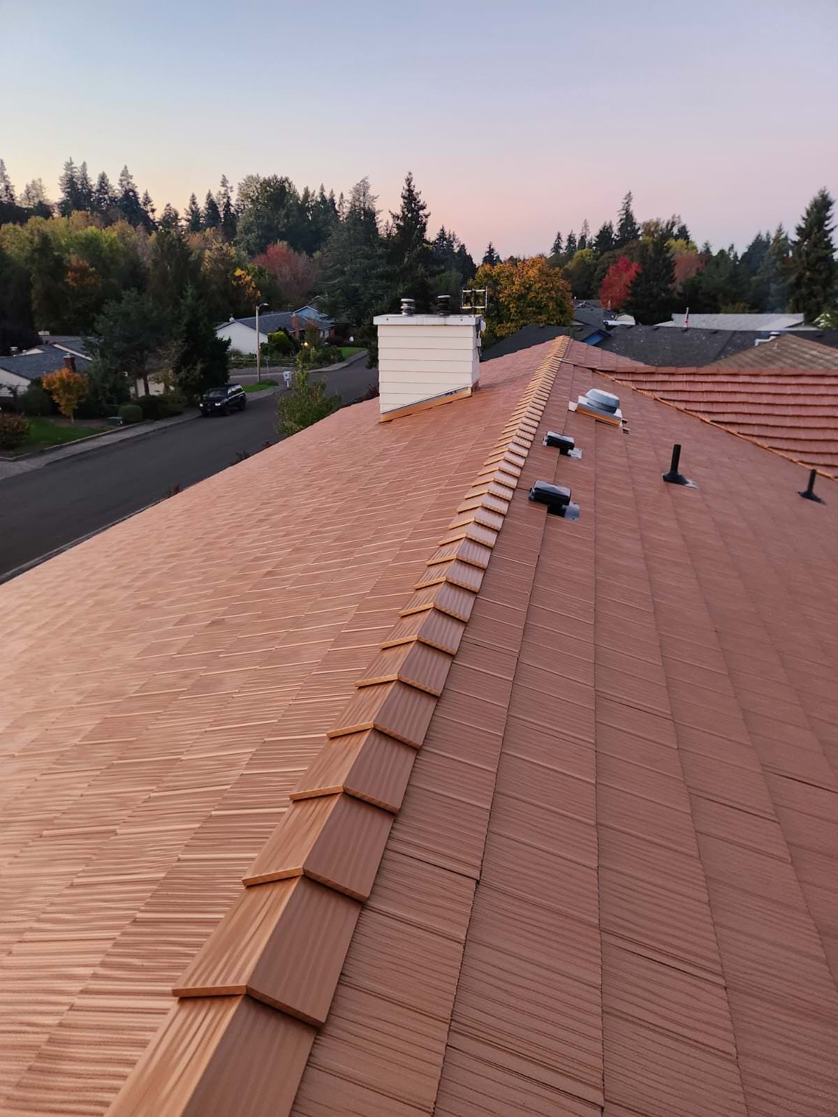 Aerial ridge-line view of Interlock aluminum shake roof in Copper Penny on a suburban ranch home in Salem, OR at golden hour.