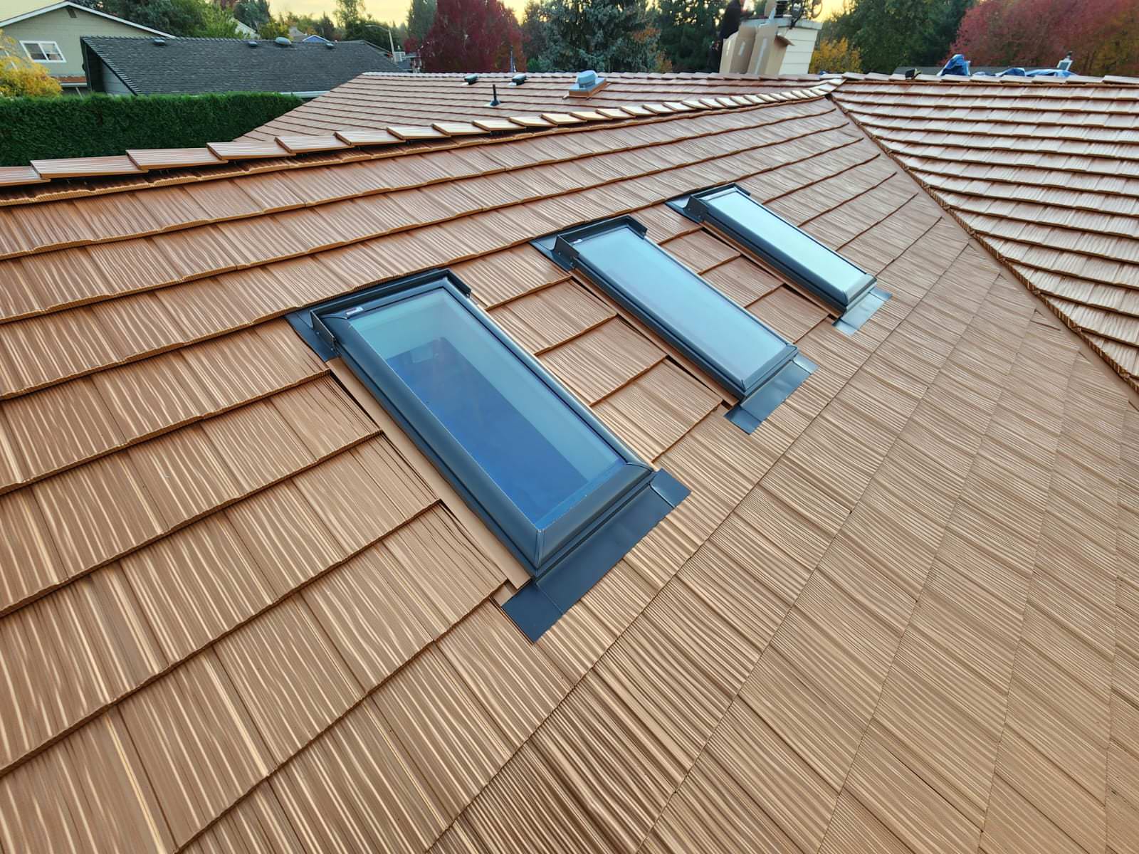 Copper Penny Interlock aluminum shake metal roof with three skylights set into a multi-hip complex roofline on a suburban home in Salem, OR.