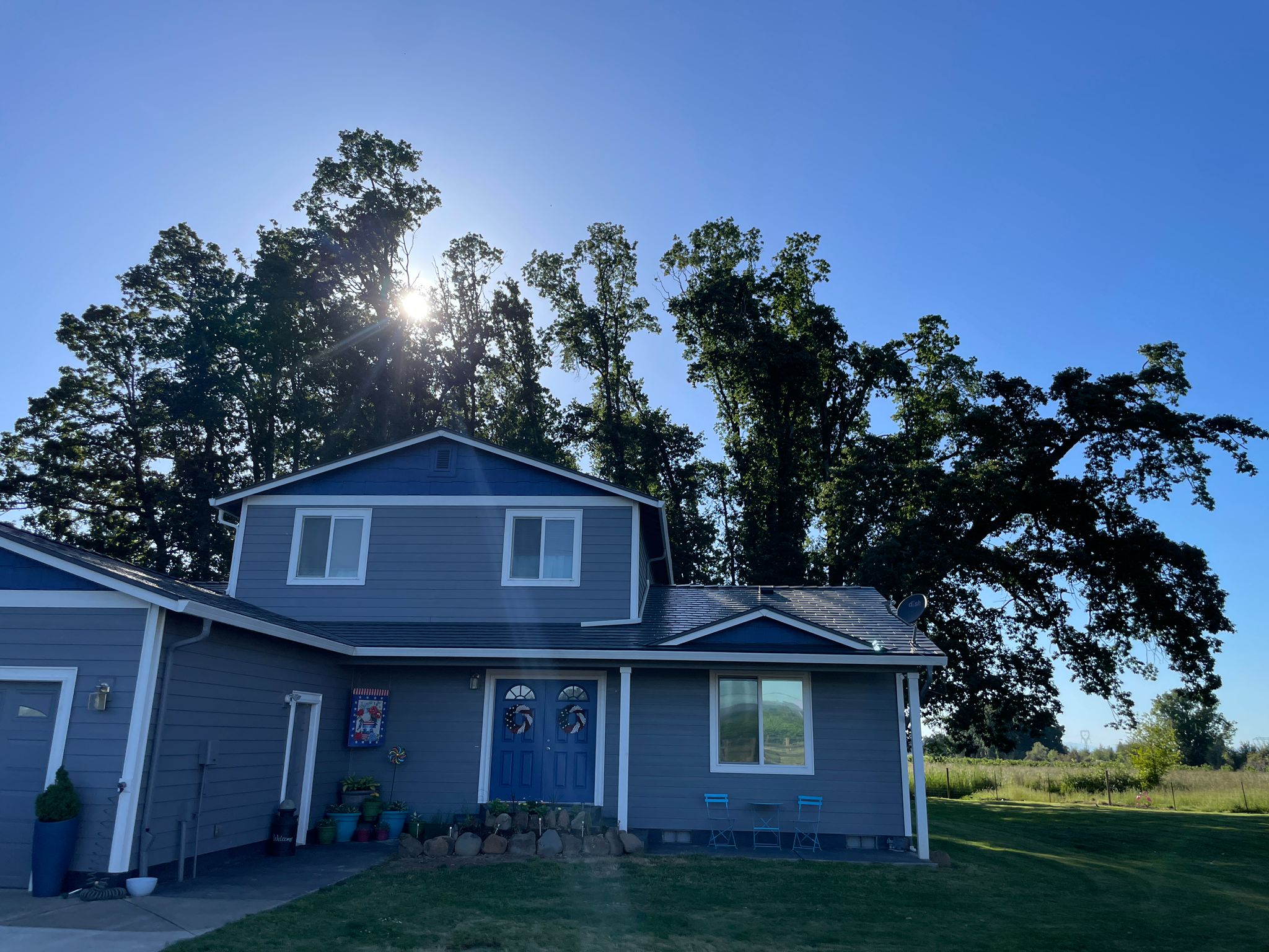 Two-story single-family home in Silverton OR with deep charcoal Interlock aluminum slate metal roof, blue-gray siding, and double front doors.