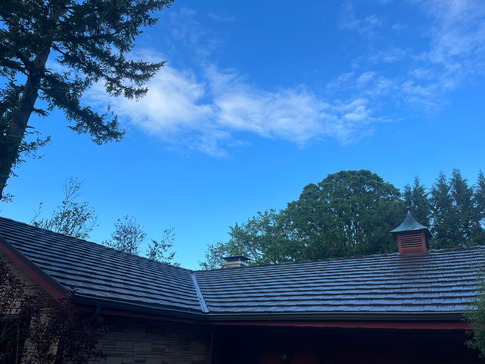 Tudor Brown Interlock aluminum shake metal roof on a single-story craftsman home in Portland, OR, with chimney, cupola vent, and surrounding evergreen trees.