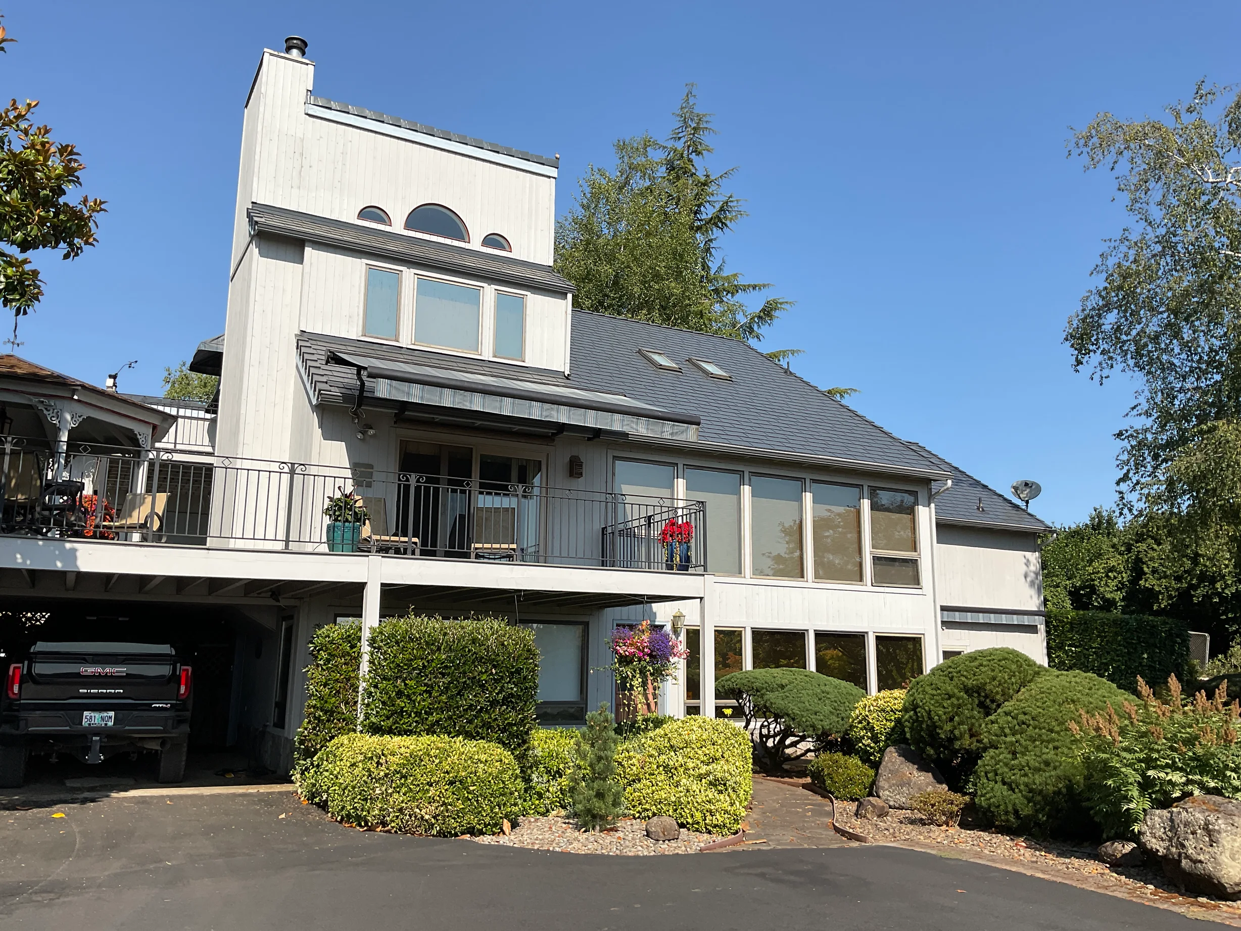Deep Charcoal Interlock Slate aluminum roof on a modern, two-storey home with a metal roof among tall trees, Amity, Oregon