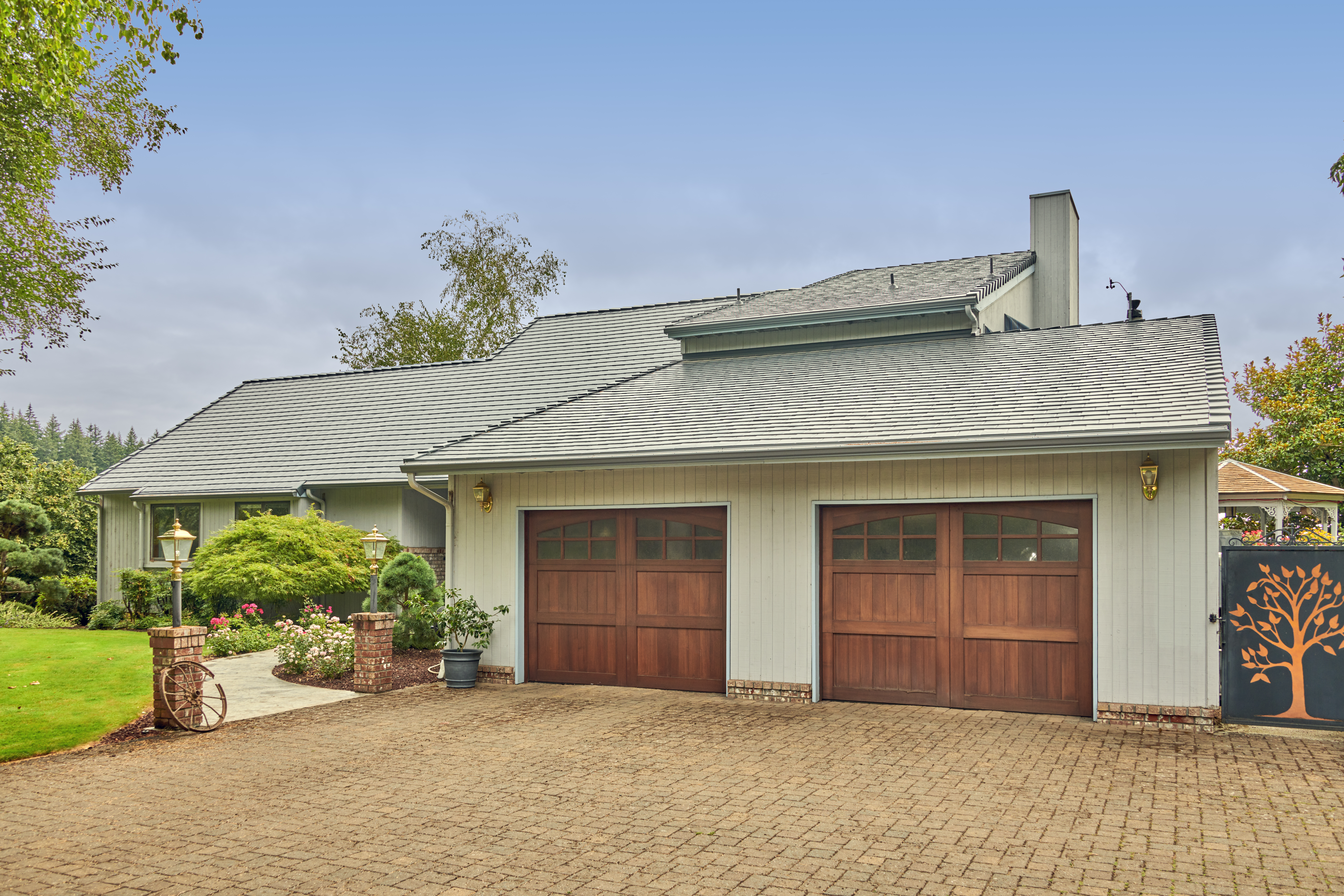 Single-story ranch home in Amity, OR with Interlock deep charcoal aluminum slate metal roofing, dual wood garage doors, and brick-paver driveway.