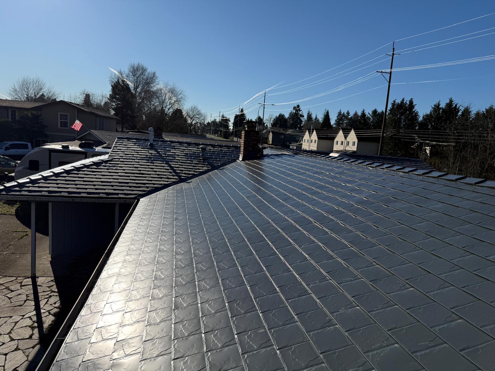 Deep charcoal Interlock aluminum slate metal roofing on a single-family ranch home in Beaverton, OR, showing full roof with chimney and valley details.