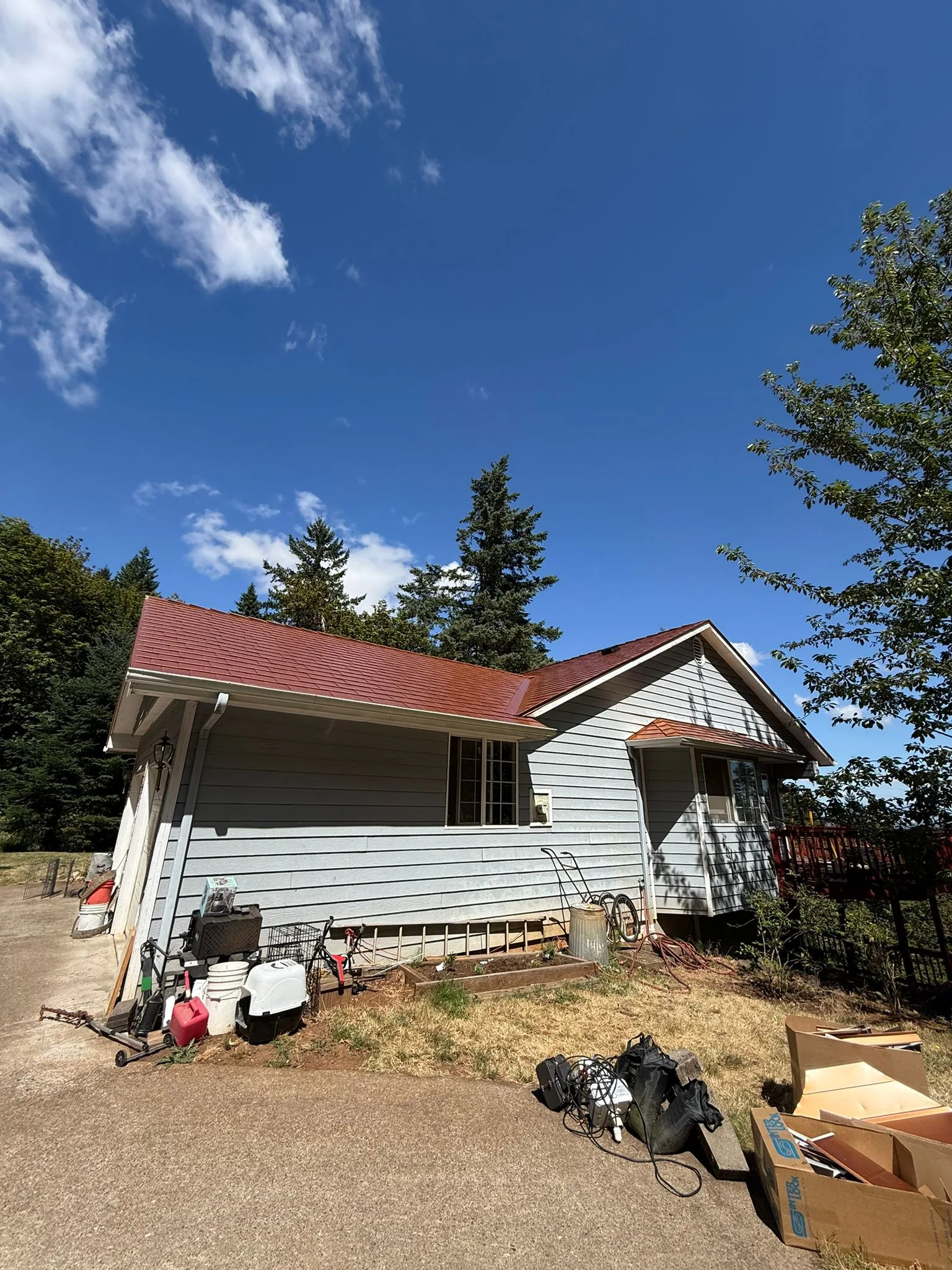 Copper Penny Interlock Slate aluminum roof on a white one-storey home with a metal roof among tall trees, Corvallis, Oregon