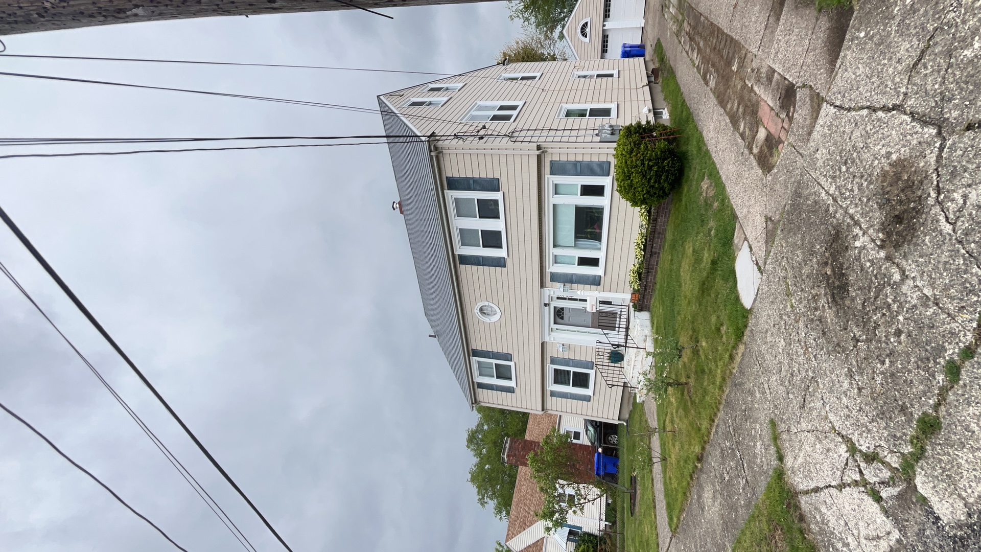Two-story Colonial home in Pawtucket, RI with a deep charcoal Interlock aluminum slate metal roof, blue shutters, and front entry steps.