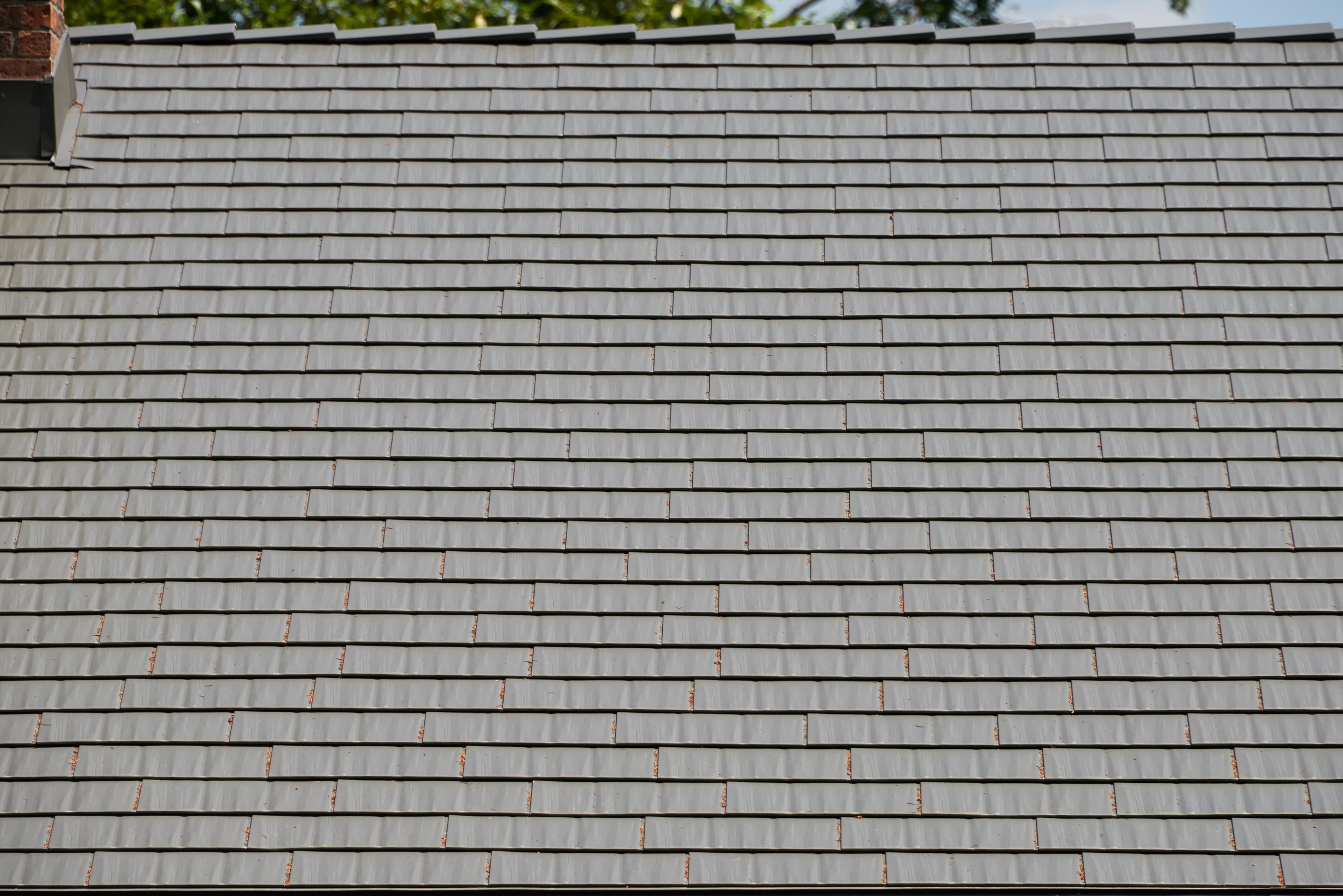Musket Grey Interlock Cedar Shingle aluminum roof on a grey two-storey home with dormers among tall pines, Arlington, Washington