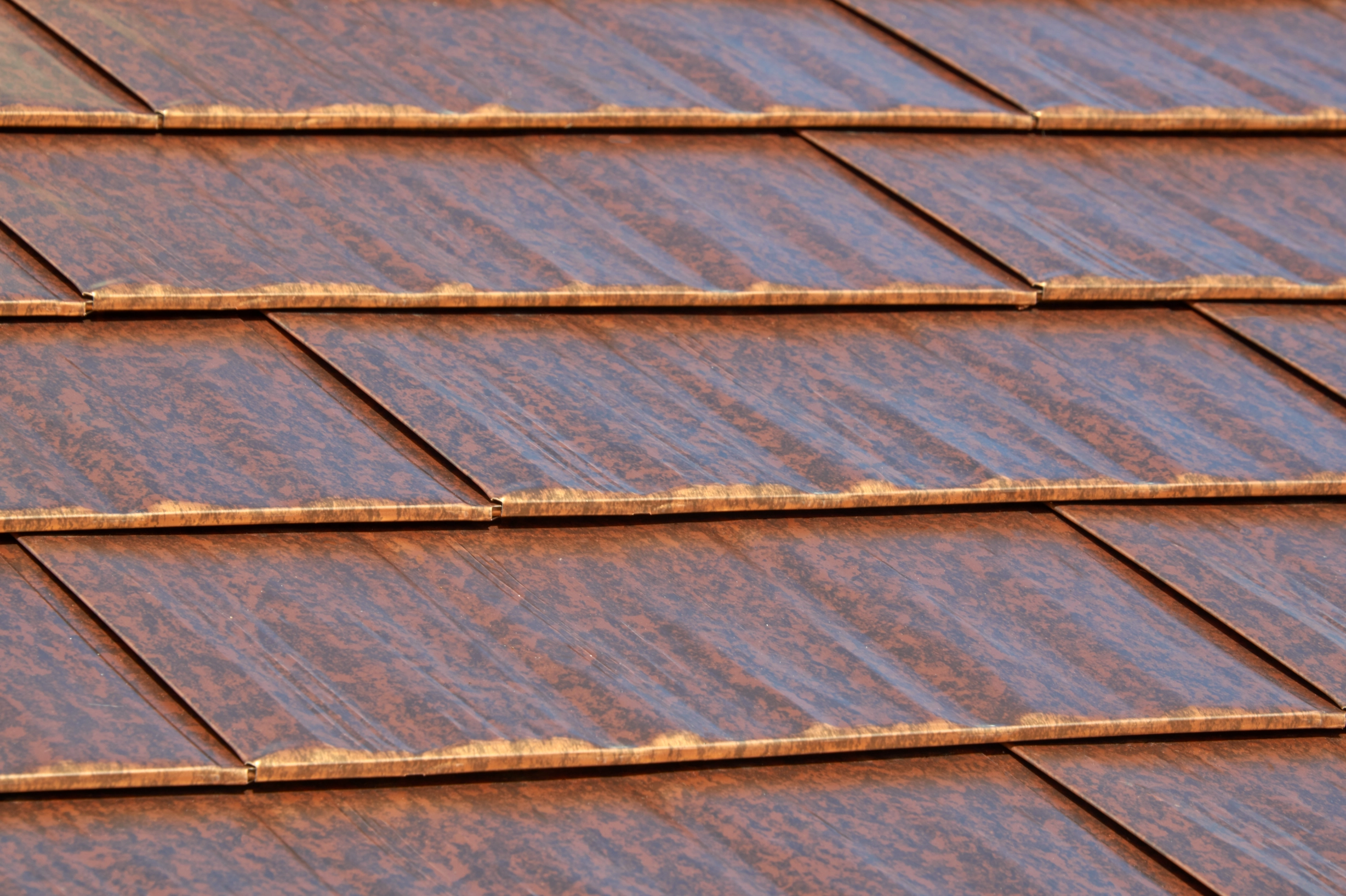 Aged Copper Interlock Cedar Shingle aluminum roof on a brown two-storey home with dormers among tall pines, Burien, Washington