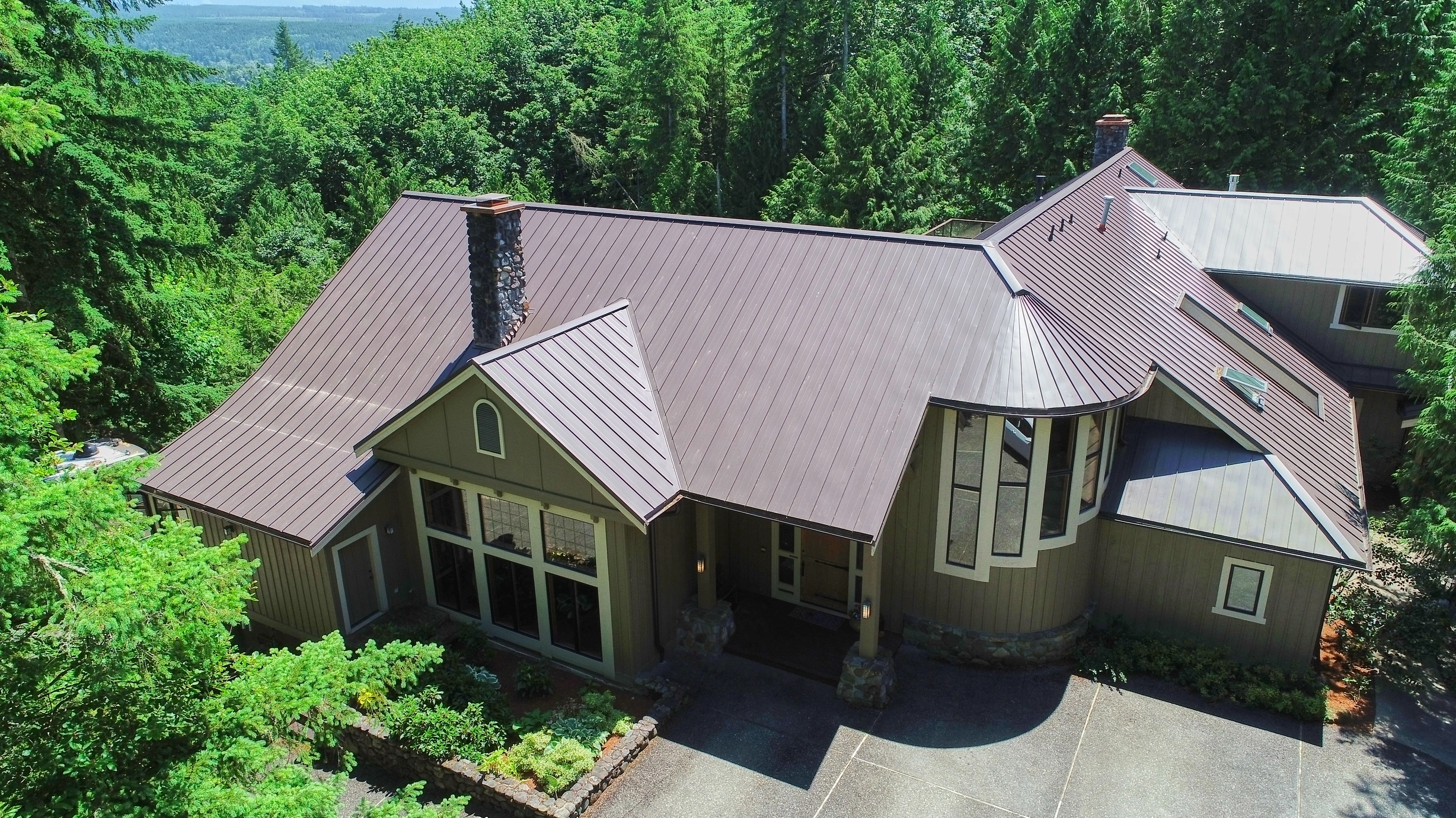 Tudor Brown Interlock Standing Seam aluminum roof on a brown one-storey Tudor home with dormers in the woods, Fall City, Washington