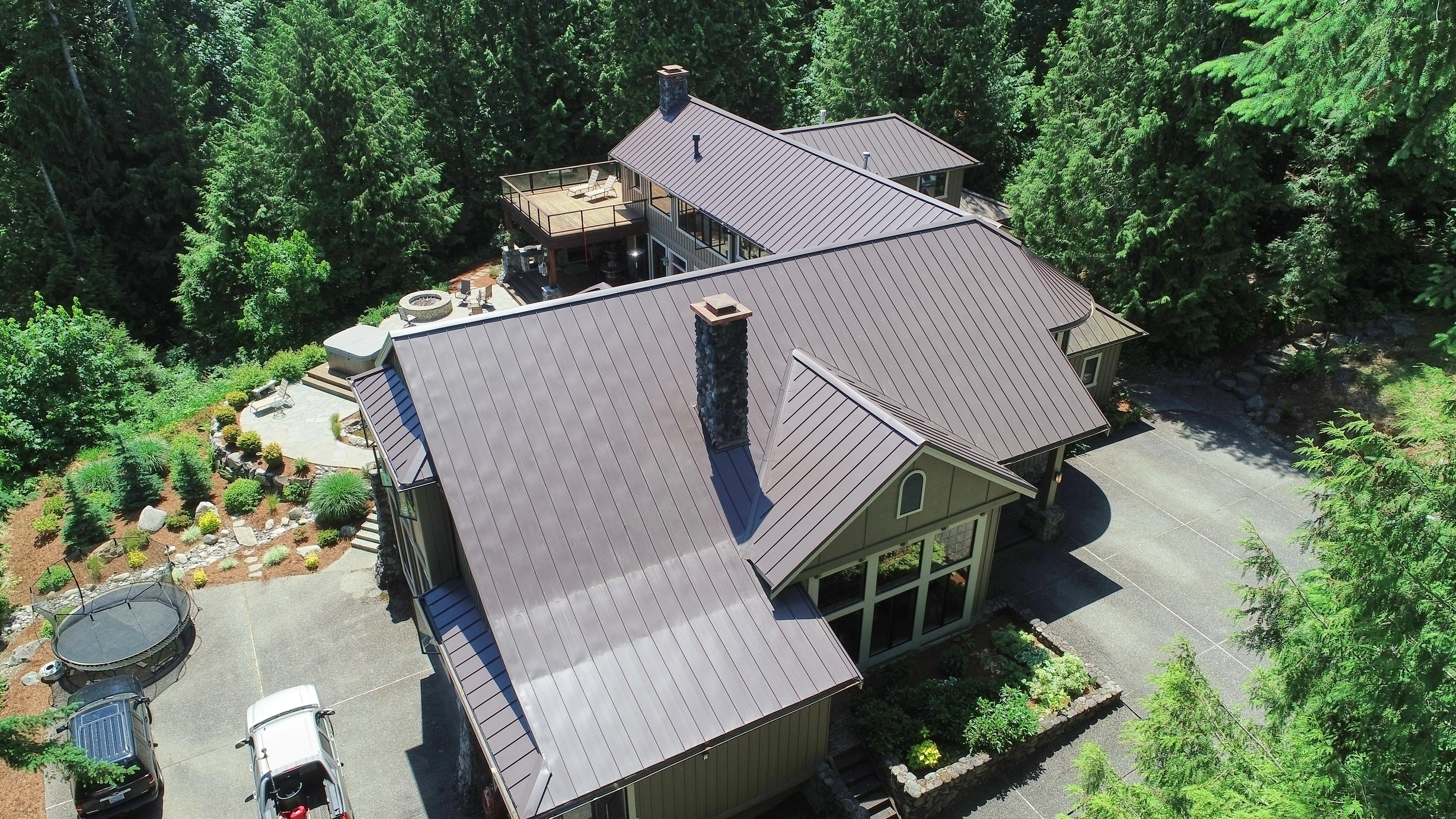 Tudor Brown Interlock Standing Seam aluminum roof on a two-storey home with a brown metal roof among tall trees, Fall City, Washington
