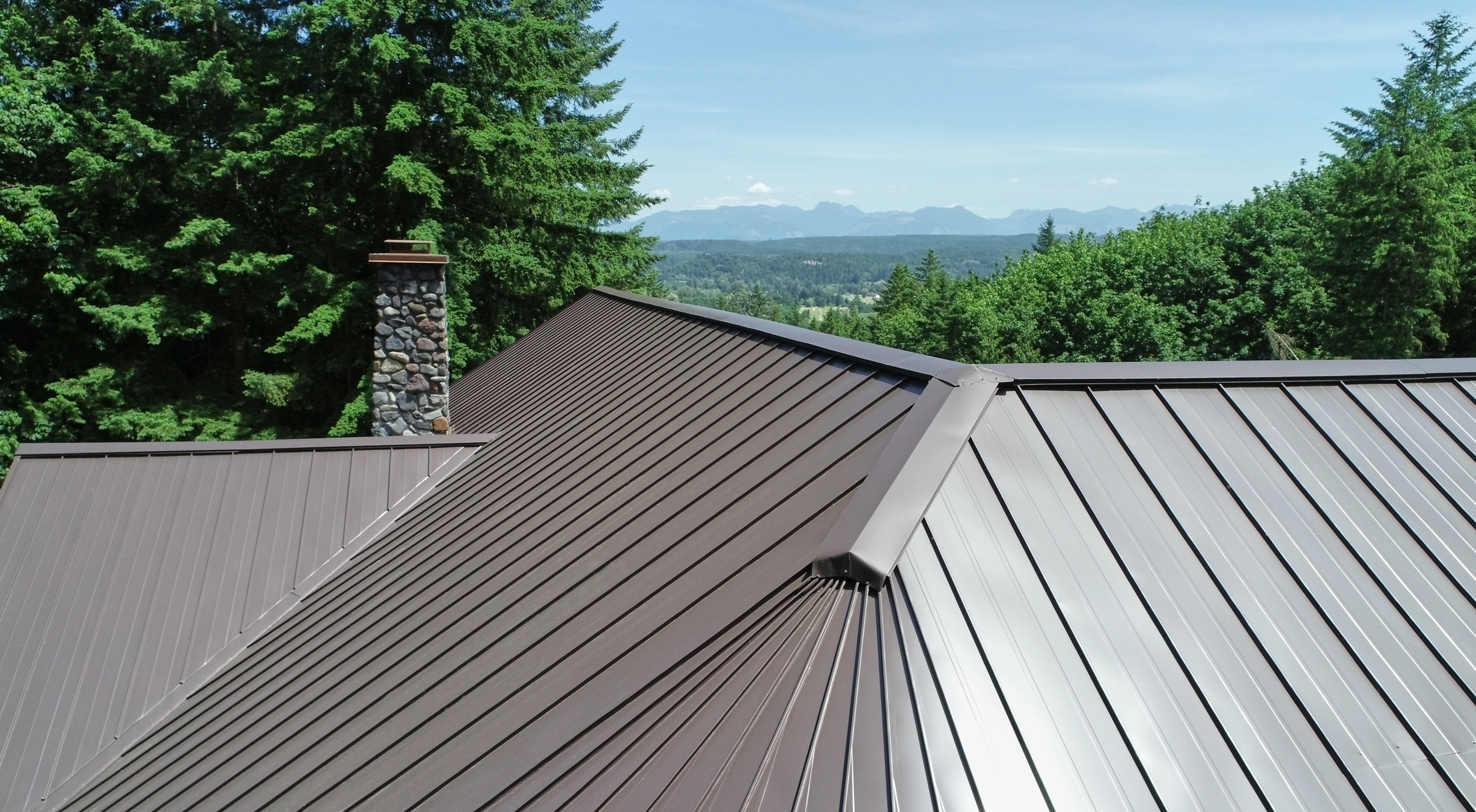 Tudor Brown Interlock Standing Seam aluminum roof on a Tudor-style home with a metal roof in a forested setting, Fall City, Washington